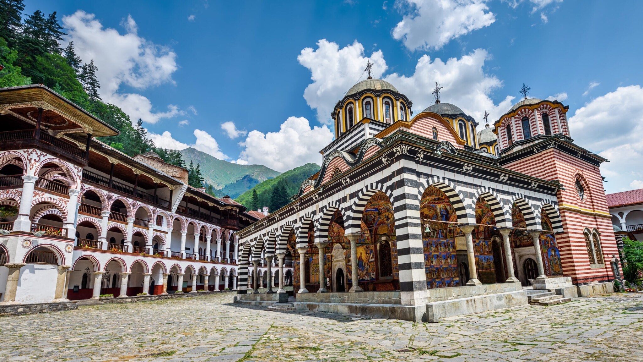 Farbenfrohe orthodoxe Klosteranlage mit mehreren Gebäuden im Gebirge.