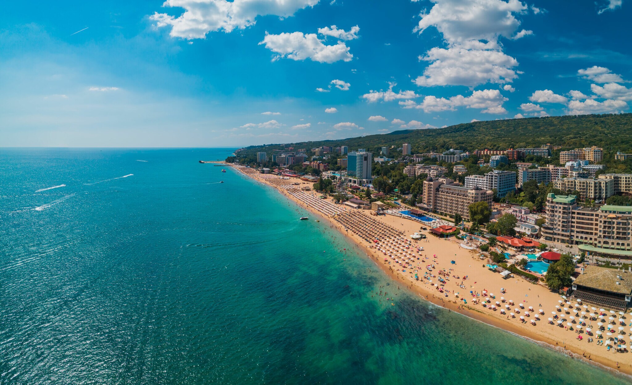 Stadt am Meer mit breitem Sandstrand mit Sonnenliegen in Reih und Glied. Stadt am Meer mit breitem Sandstrand mit Sonnenliegen in Reih und Glied.