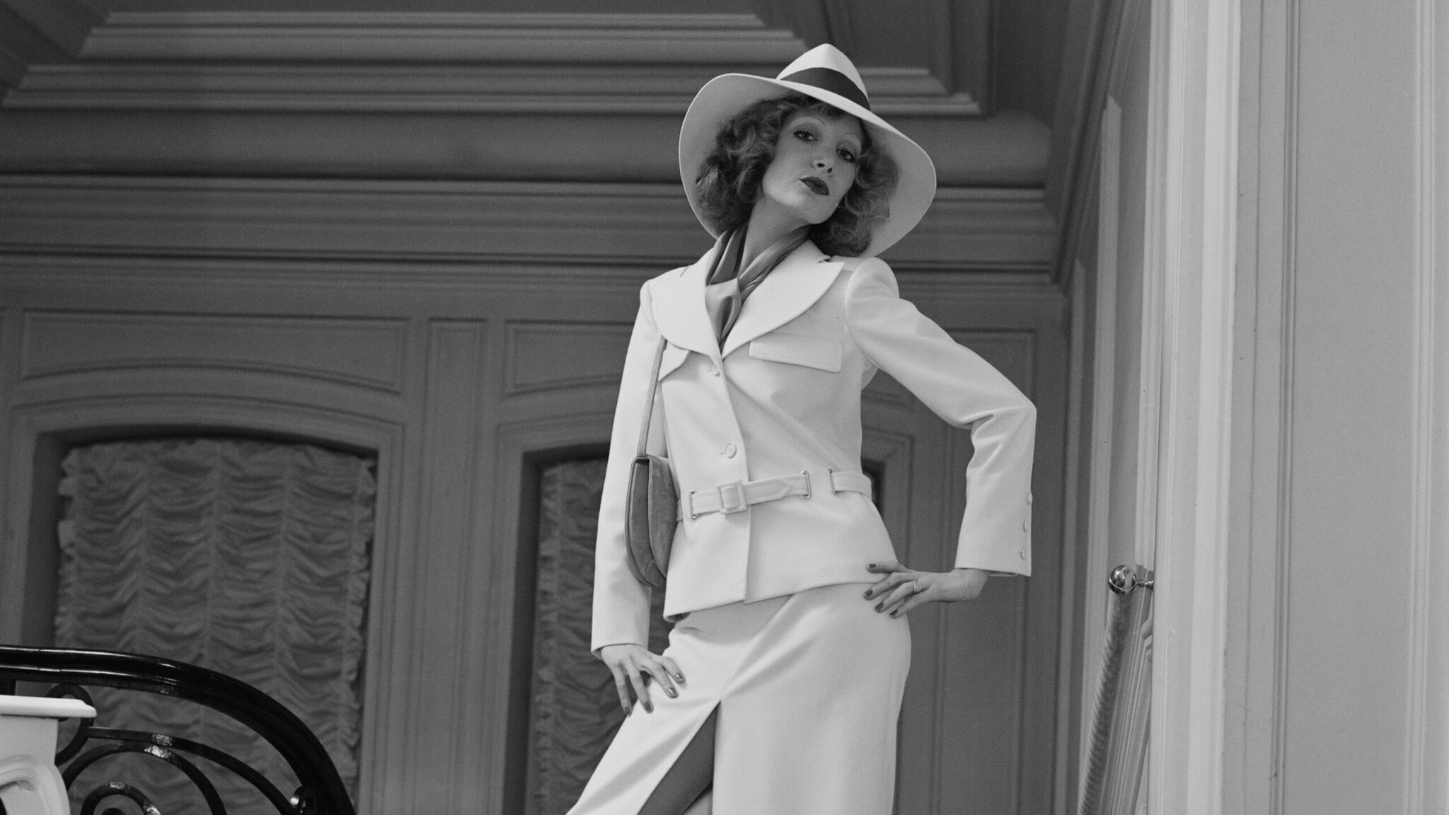 Marlene Dietrich posiert in einem weißen Kostümkleid mit Strohhut in einem Treppenaufgang. Marlene Dietrich posiert in einem weißen Kostümkleid mit Strohhut in einem Treppenaufgang.