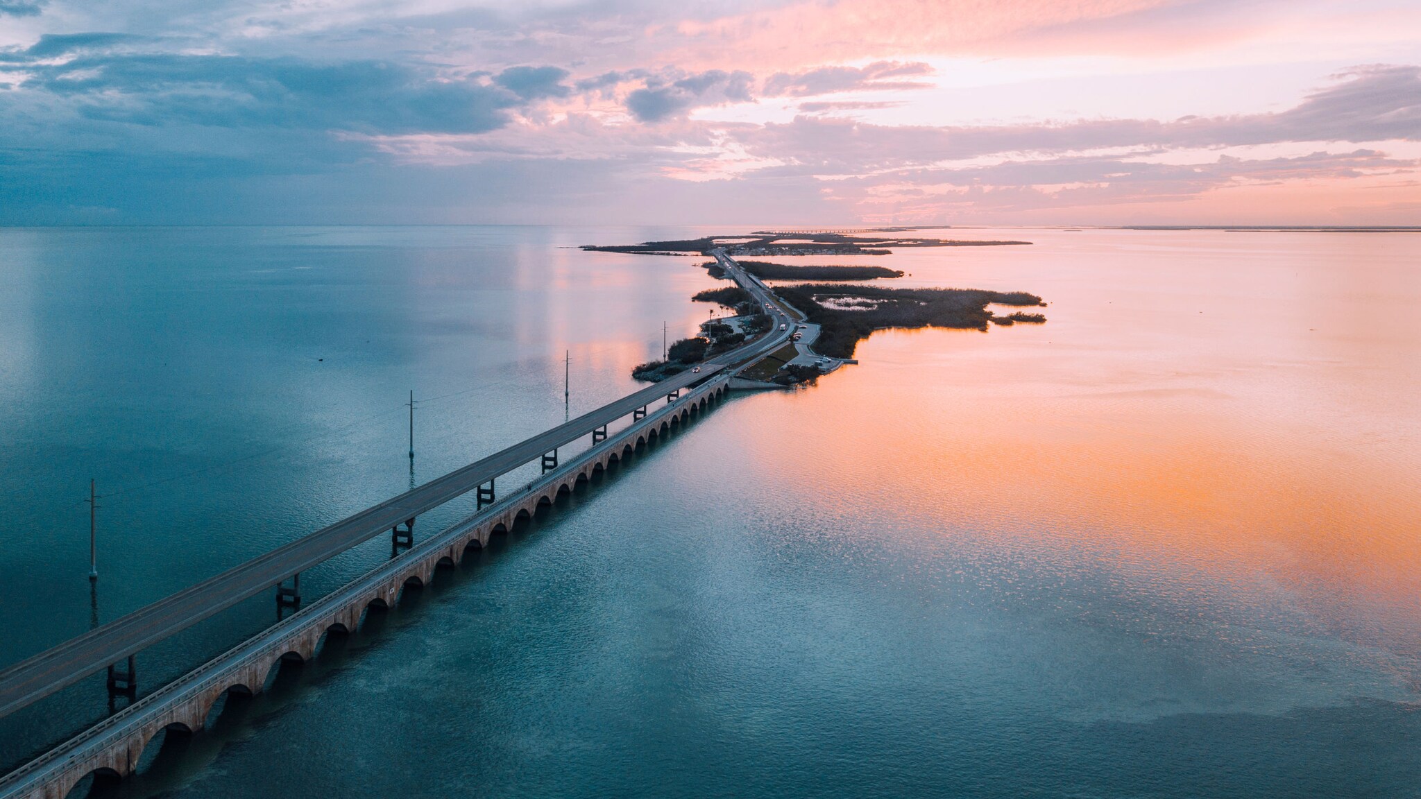 Eine lange, zweispurige Autobrücke über Wasser, die kleine Inseln miteinander verbindet bei Sonnenuntergang. Eine lange, zweispurige Autobrücke über Wasser, die kleine Inseln miteinander verbindet bei Sonnenuntergang.