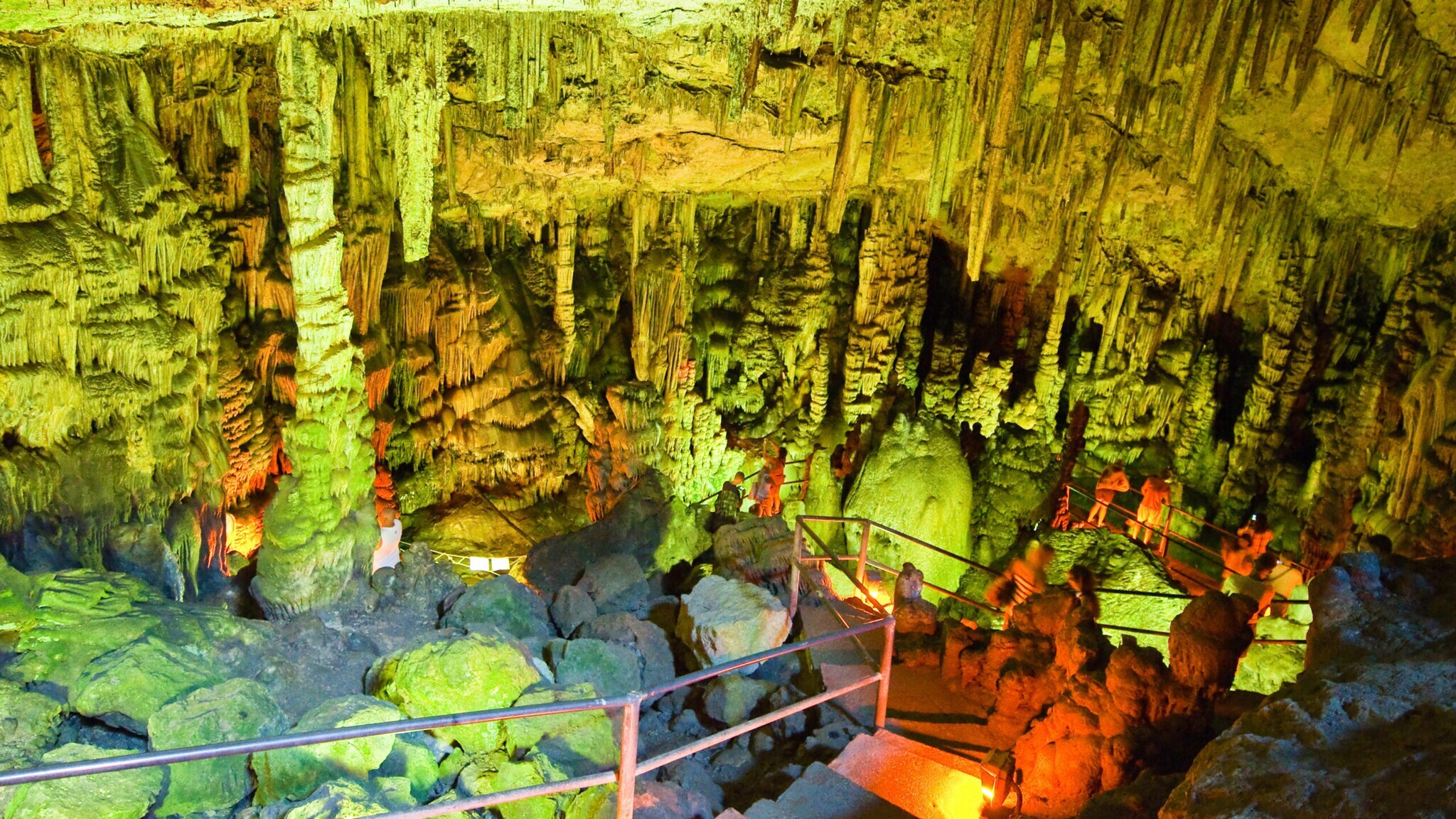 Personen in einer grün beleuchteten Tropfsteinhöhle.