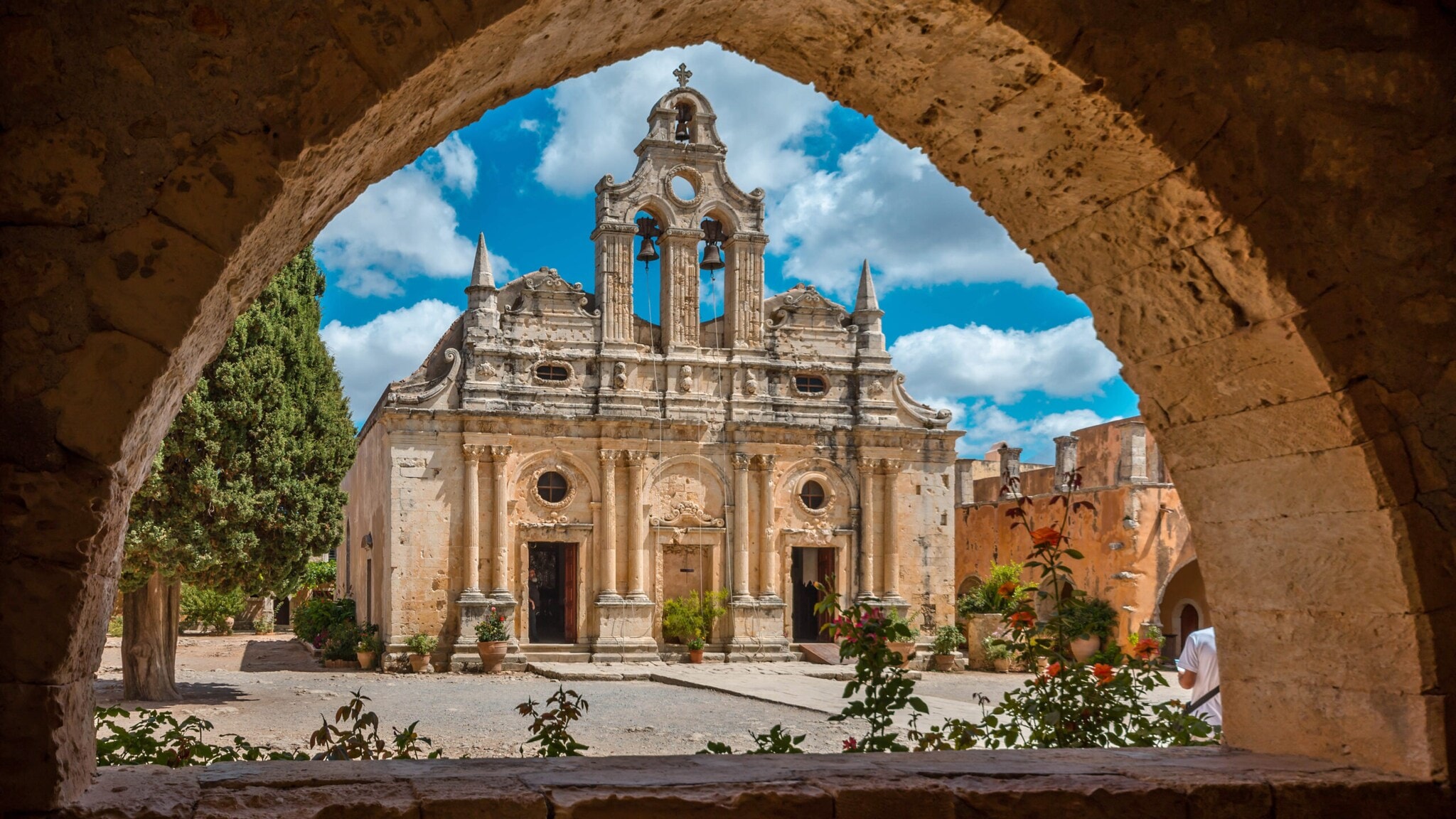 Blick auf ein altes orthodoxes Kloster aus Sandstein unter blauem Himmel durch den Bogen einer Felsmauer. Blick auf ein altes orthodoxes Kloster aus Sandstein unter blauem Himmel durch den Bogen einer Felsmauer.