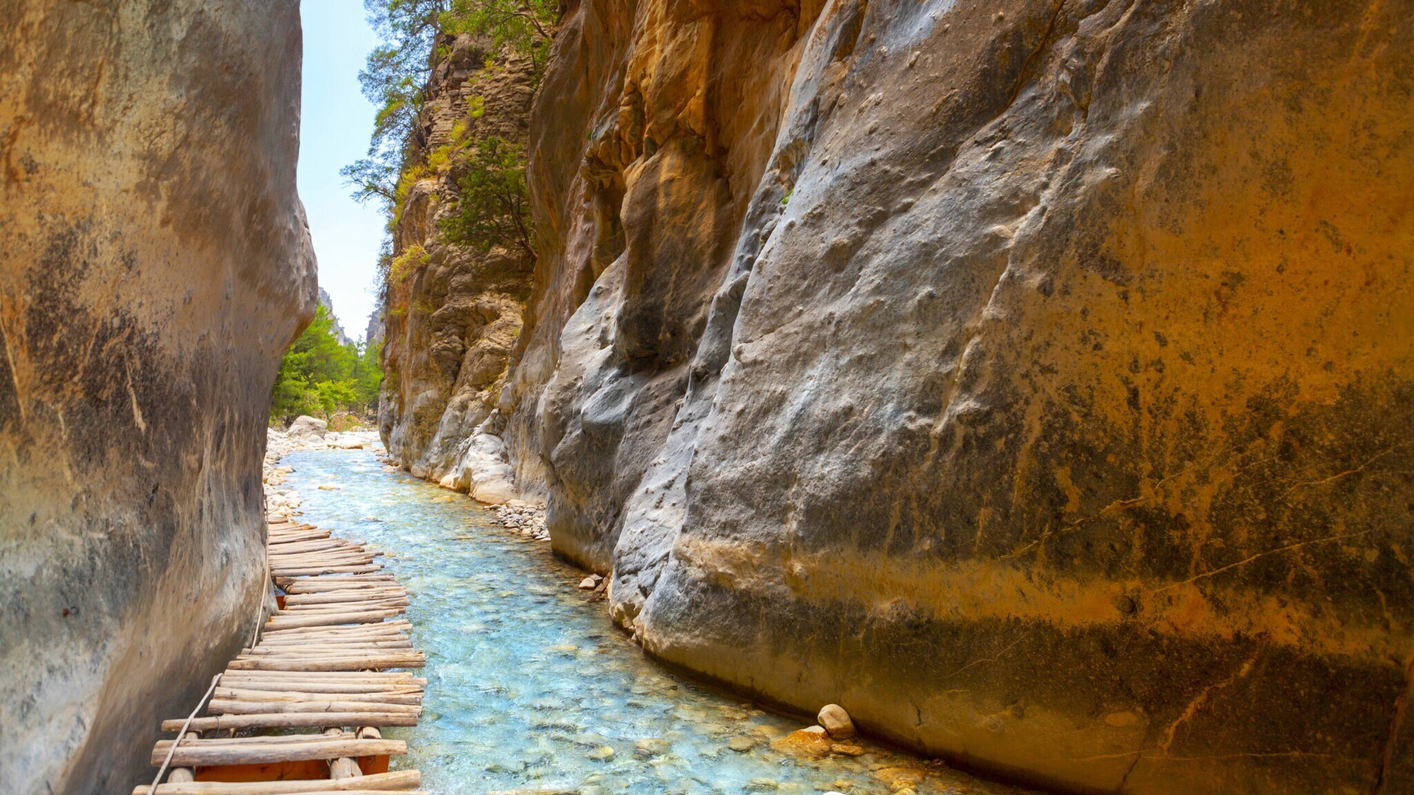 Holzweg über ein flaches Gewässer in einer Schlucht mit steilen Felswänden.