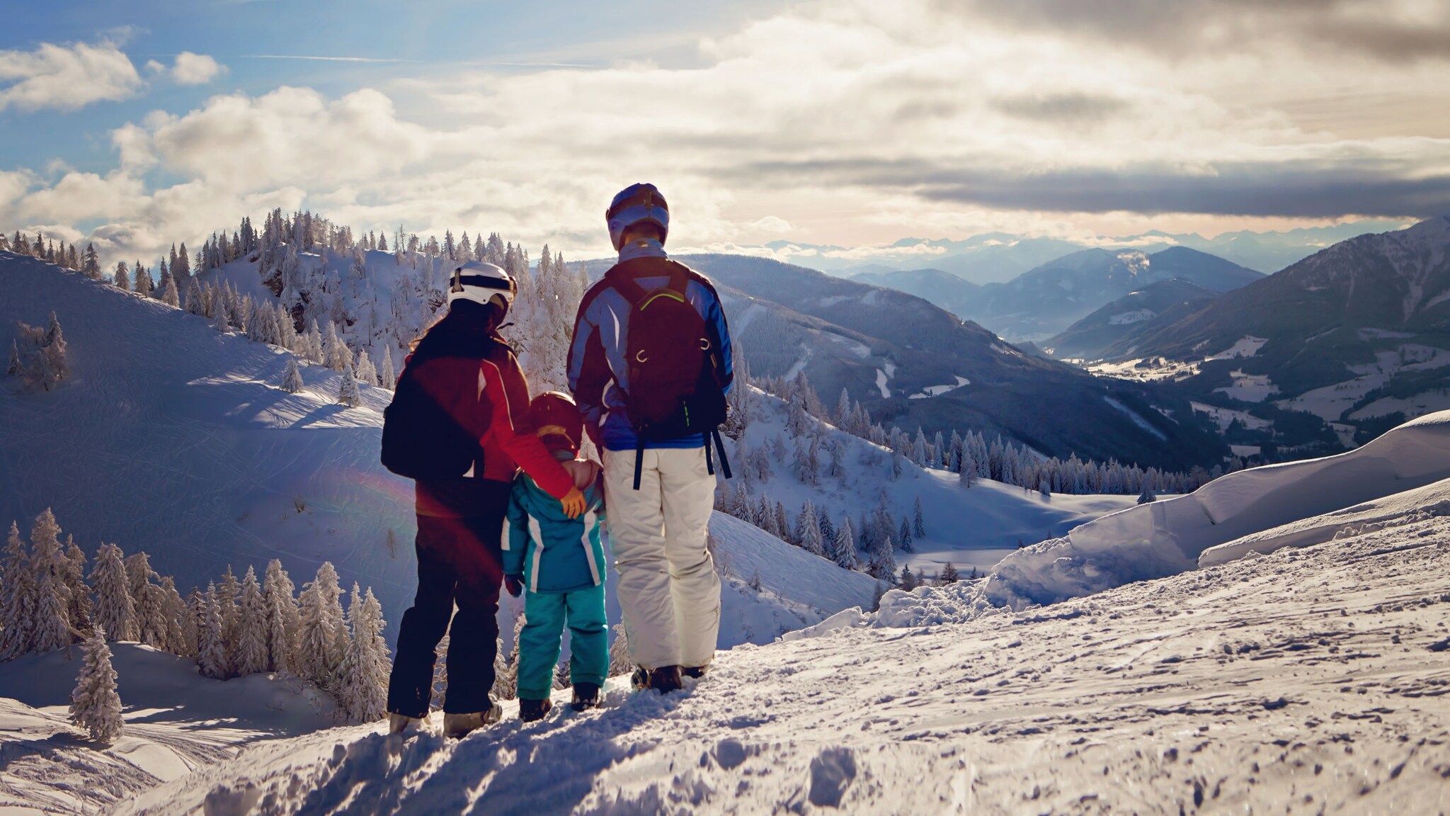 Drei Personen, darunter ein Kind, stehen auf einer Skipiste.