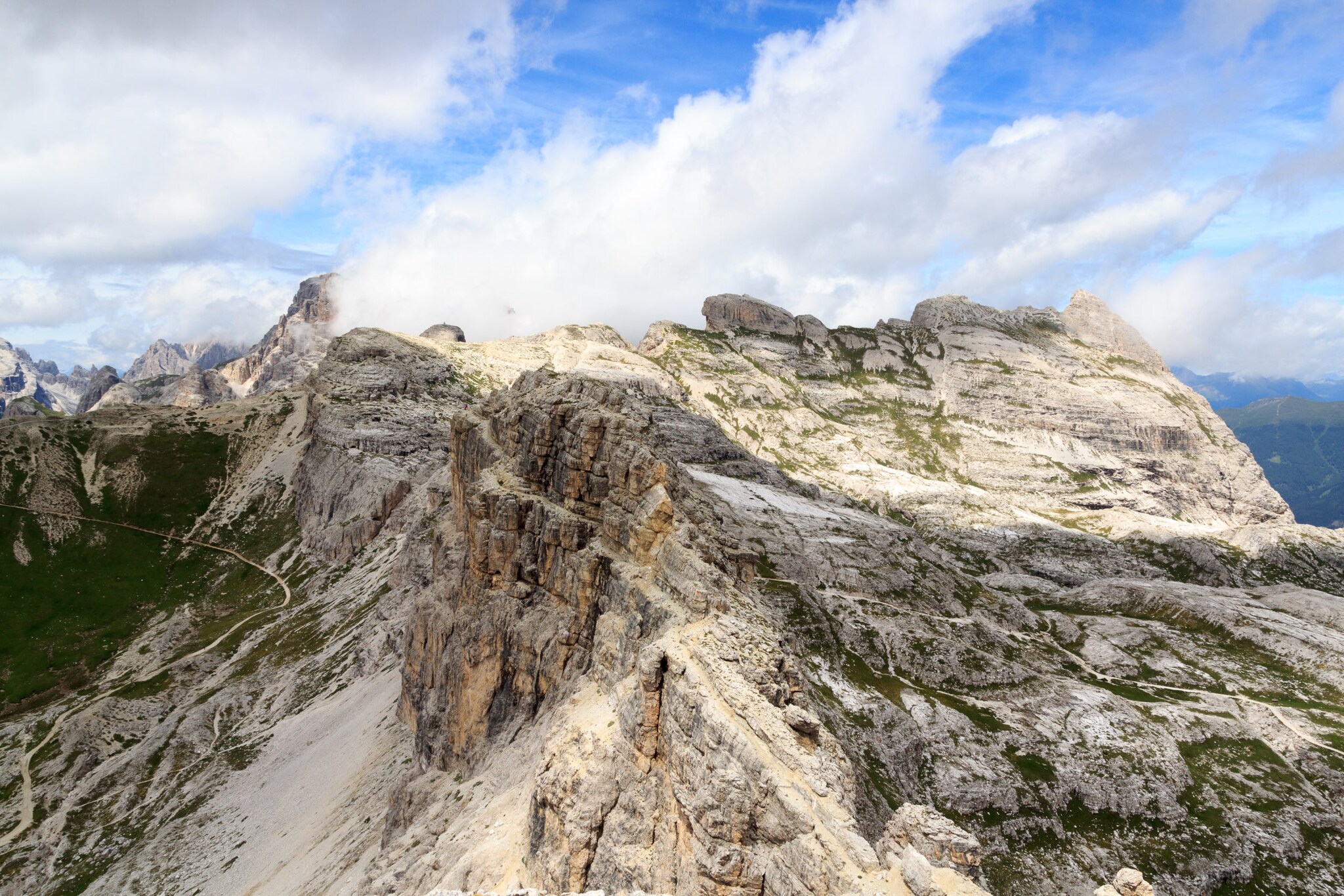 Blick auf eine karge Berglandschaft, blauen Himmel und weiße Wolken in den Dolomiten.