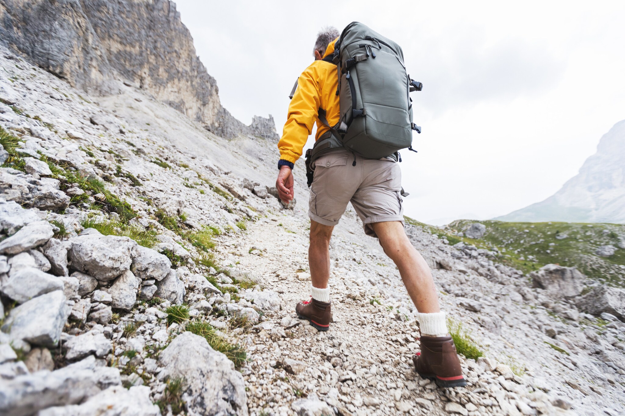 Wandernde Person von hinten in einer kargen Berglandschaft.