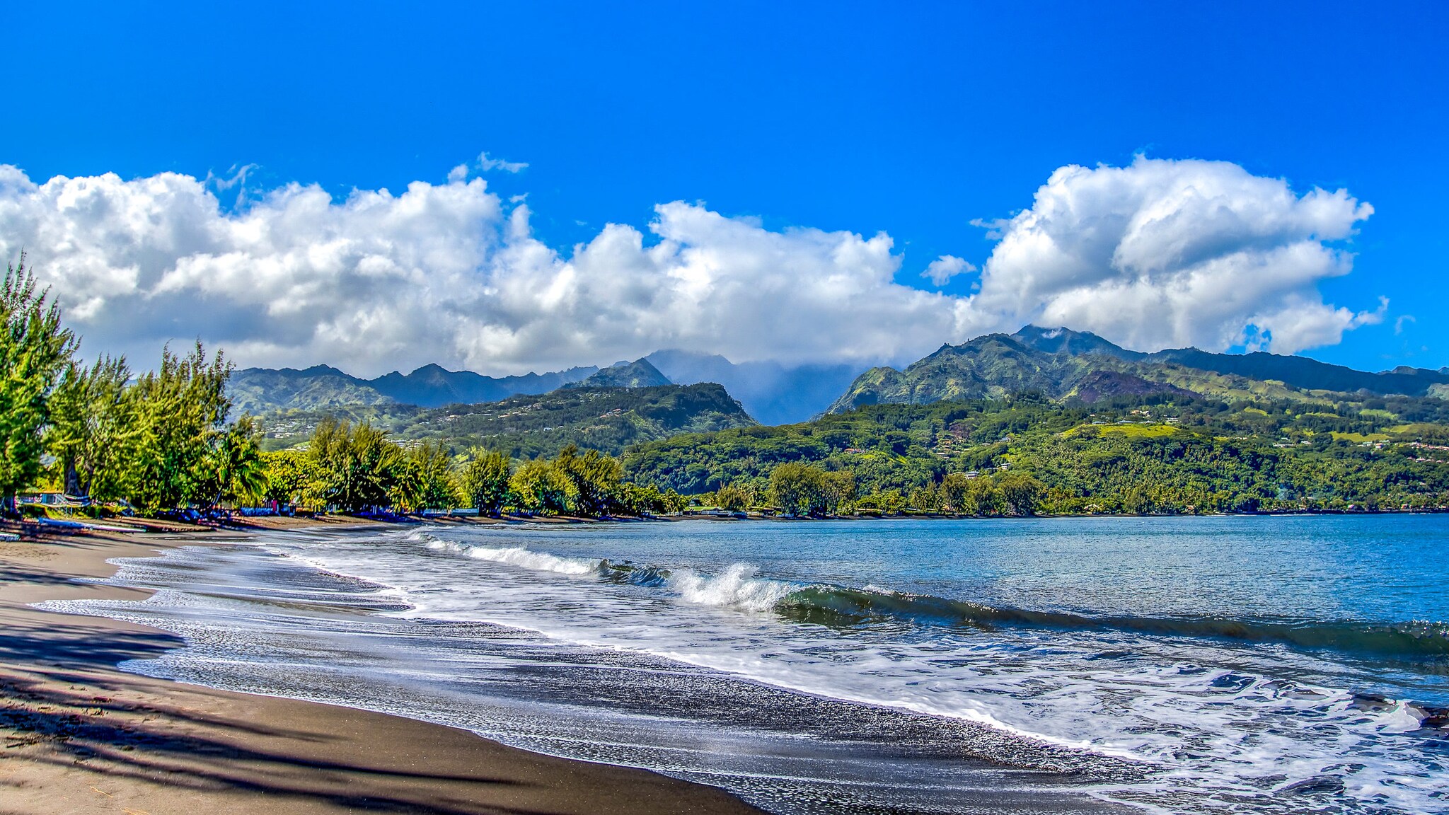 Menschenleerer Strand mit grüner Vegetation vor Berglandschaft. Menschenleerer Strand mit grüner Vegetation vor Berglandschaft.