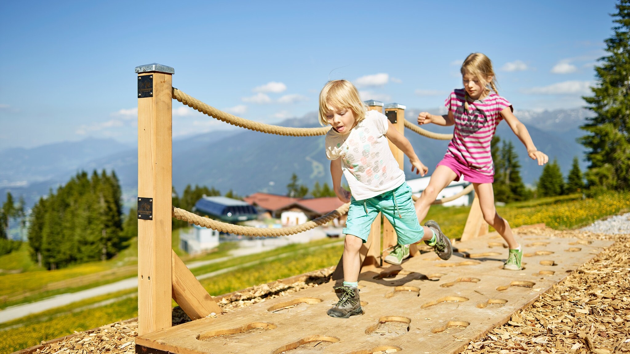 Zwei Kinder laufen auf einem Parkour in einer Berglandschaft. Zwei Kinder laufen auf einem Parkour in einer Berglandschaft.