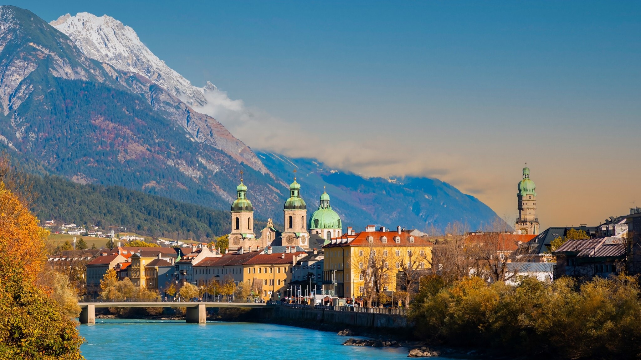 Skyline der Innsbrucker Altstadt am Fluss vor Bergpanorama.