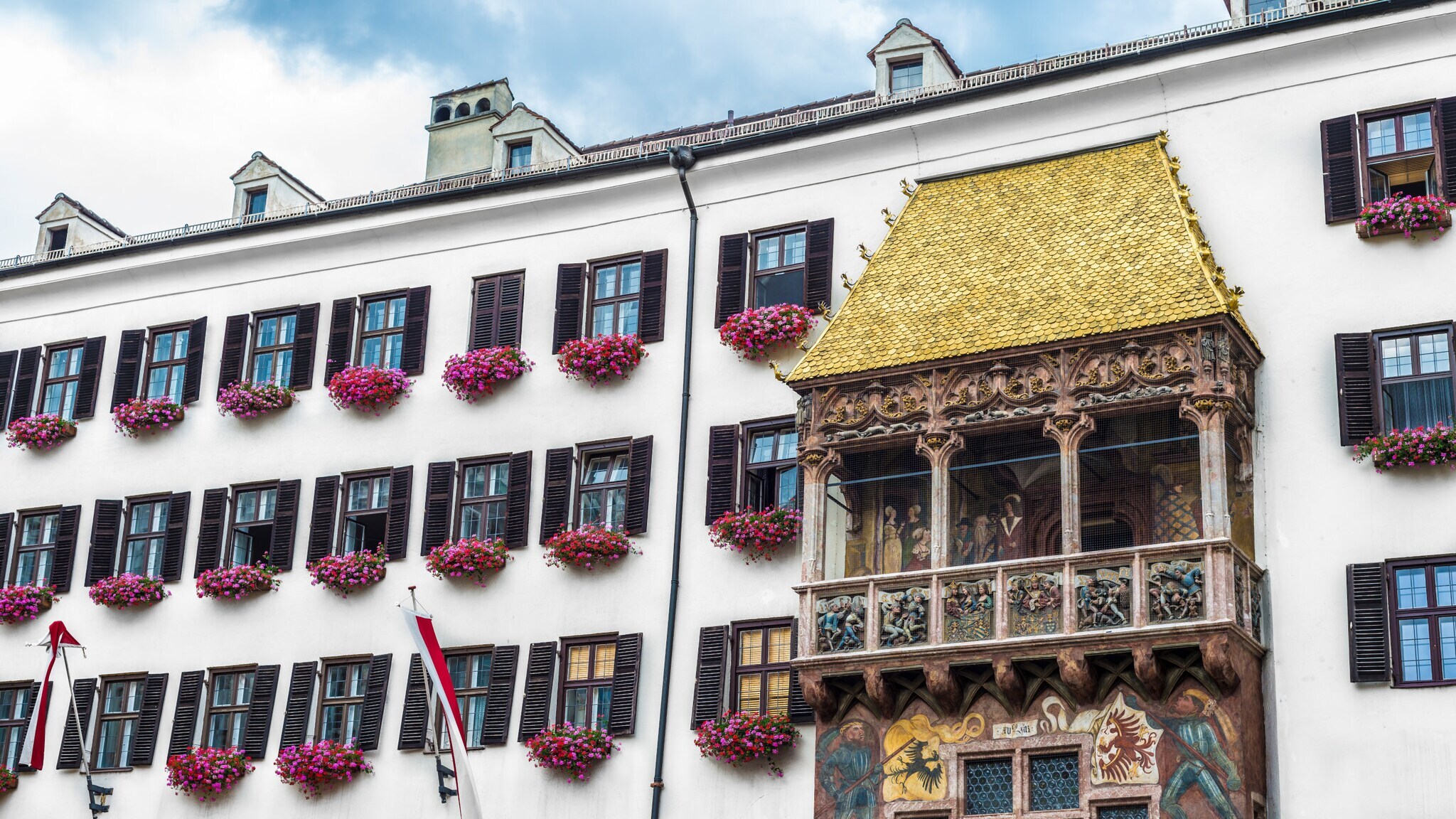 Hausfassade mit Balkon mit prunkvollen Verzierungen und goldenem Dach.