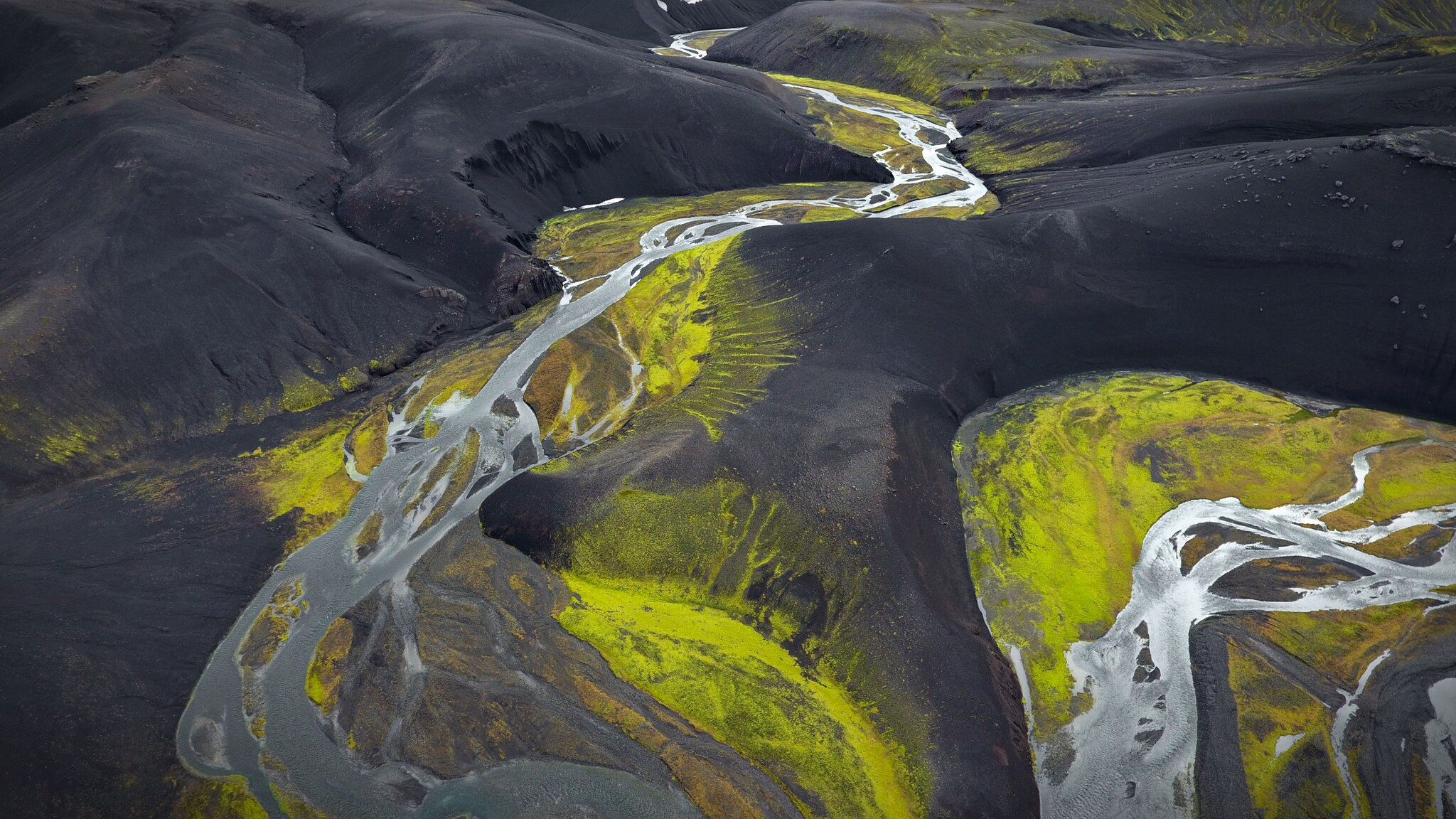 Aufsicht einer Hochlandpiste mit Schotterstraßen in einer schwarzen Lavalandschaft.