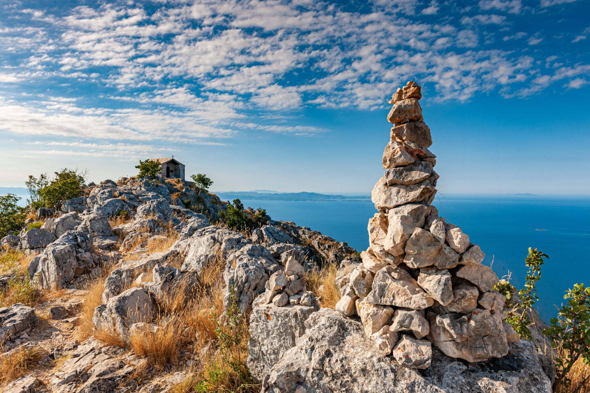 Blick von einem felsigen Berg aufs blaue Meer.