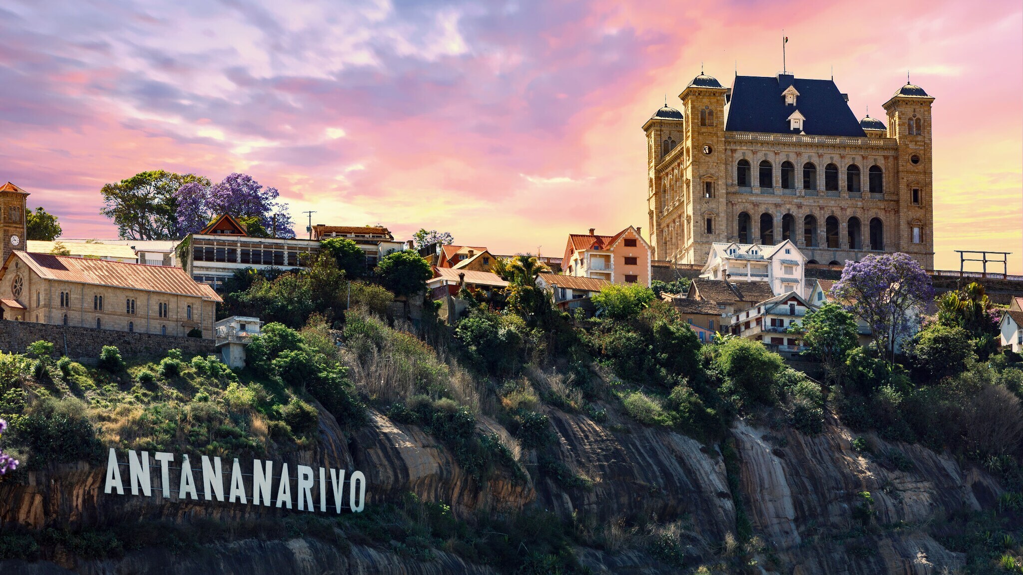 Ortschaft mit Palastgebäude auf einer Felsklippe mit einem befestigten Schriftzug Antananarivo in weißen Lettern.