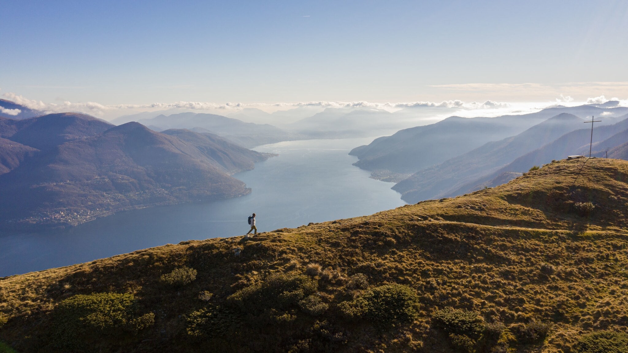 Panoramaaufnahme von einem Mann mit Rucksack auf einem Berg und dem Lago Maggiore im Hintergrund. Panoramaaufnahme von einem Mann mit Rucksack auf einem Berg und dem Lago Maggiore im Hintergrund.