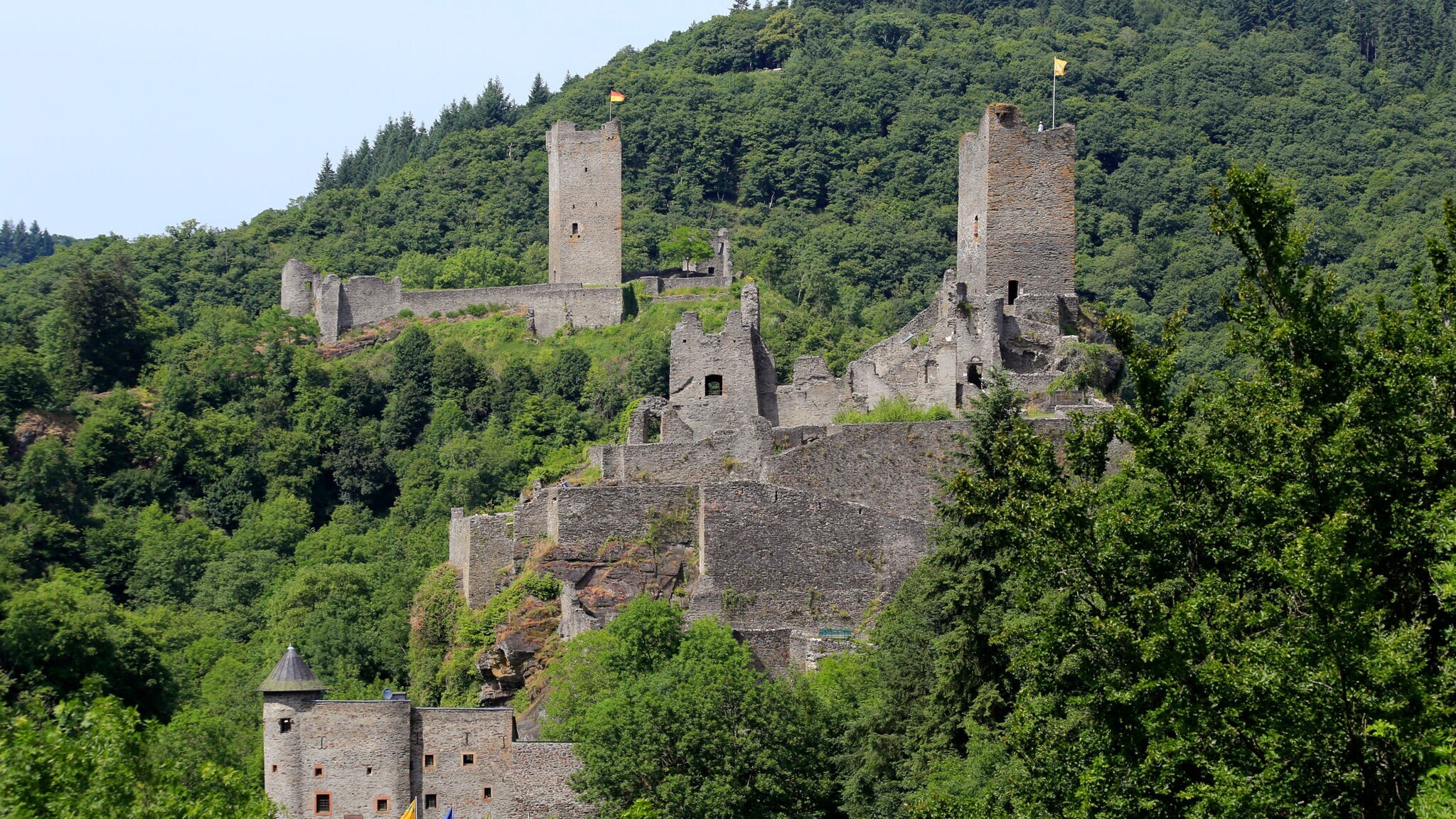 Ausblick auf die Oberburg und Niederburg in Manderscheid, umgeben von grünen Baumkronen. Ausblick auf die Oberburg und Niederburg in Manderscheid, umgeben von grünen Baumkronen.