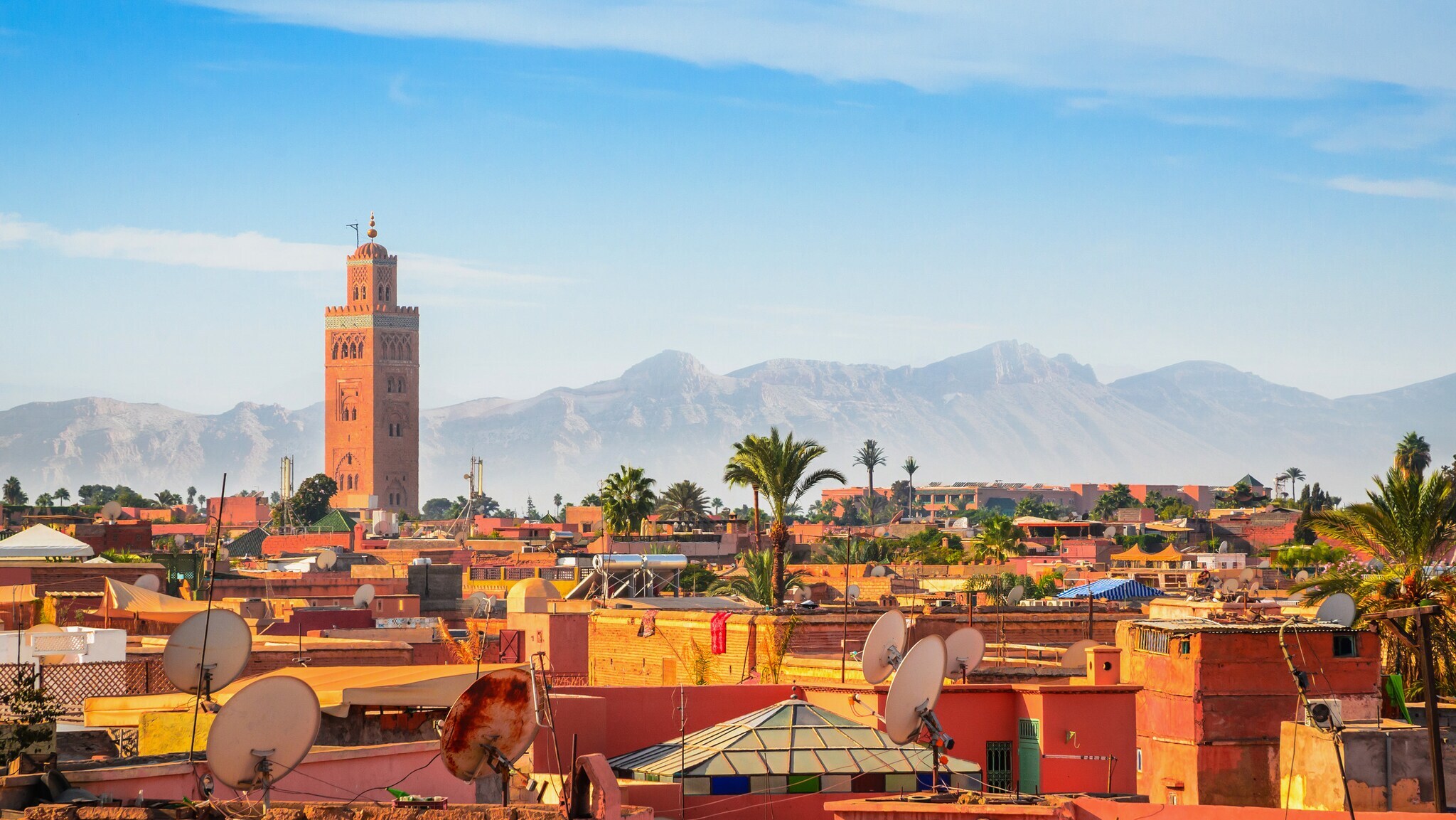Stadtpanorama von Marrakesch mit Minarett vor Gebirgskette im Hintergrund unter blauem Himmel. Stadtpanorama von Marrakesch mit Minarett vor Gebirgskette im Hintergrund unter blauem Himmel.