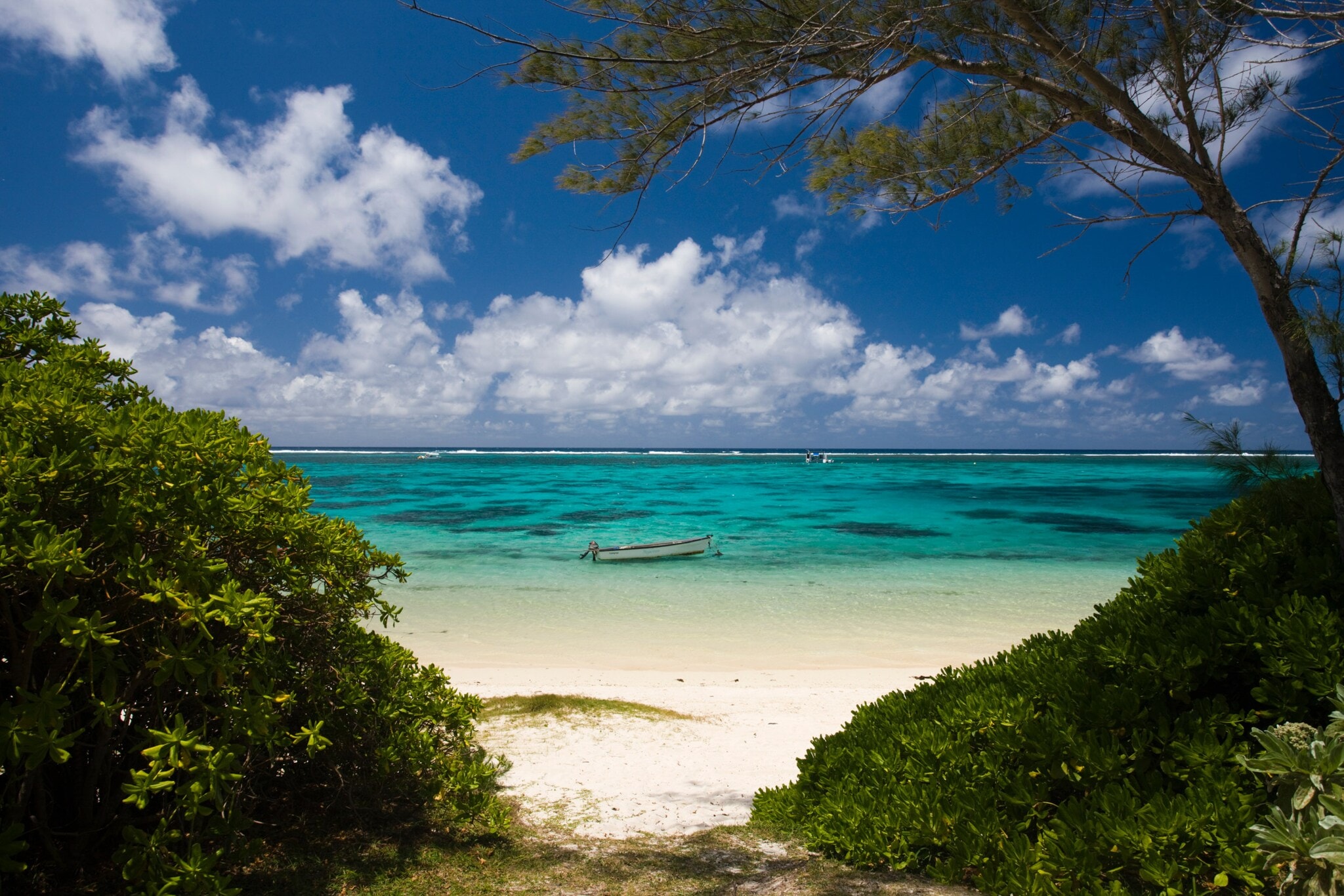Ein Fischerboot im türkisblauen Meer an einem weißen Sandstrand. Ein Fischerboot im türkisblauen Meer an einem weißen Sandstrand.