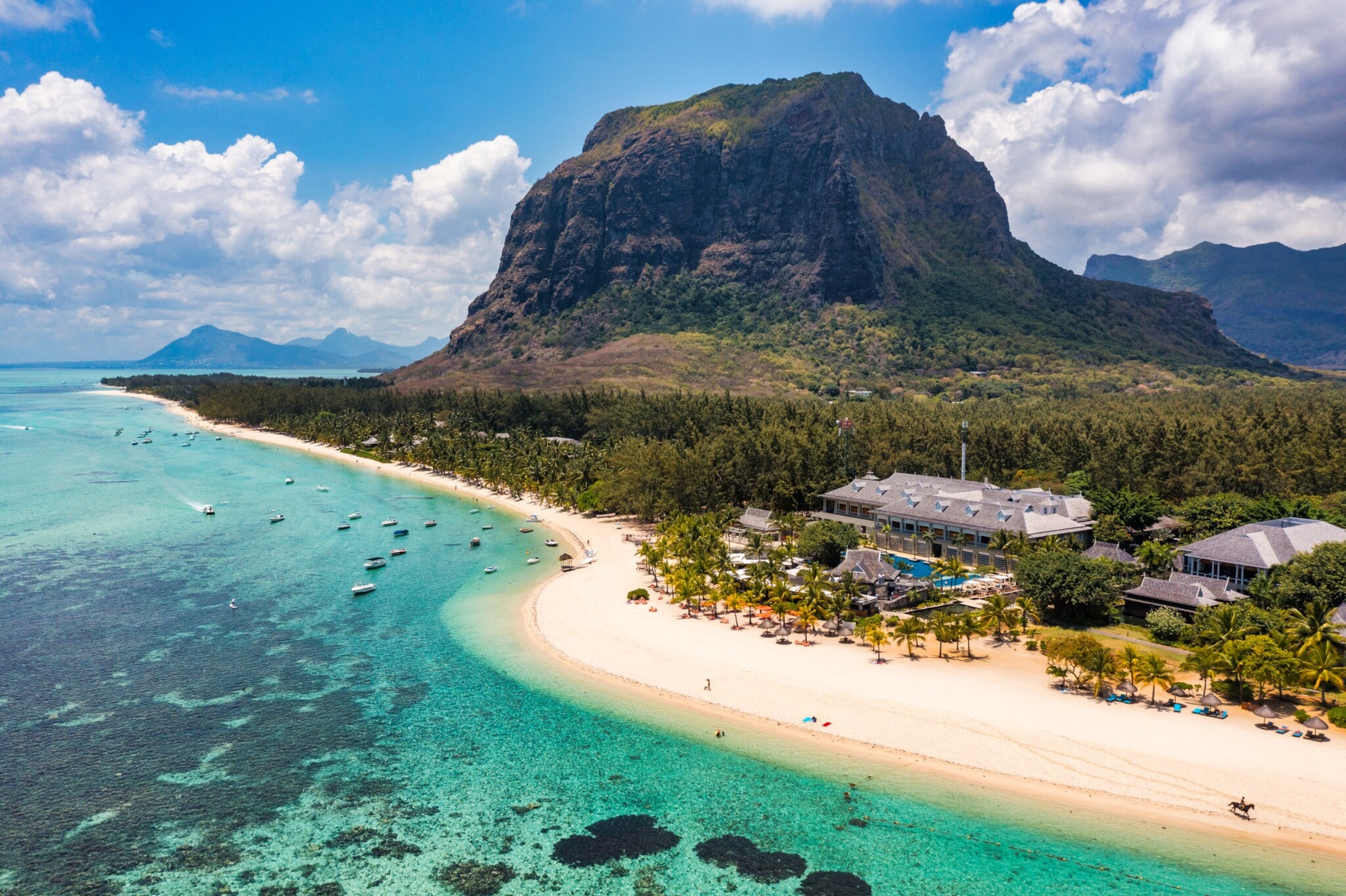 Küstenpanorama mit Hotelresort an einem palmengesäumten, weißen Sandstrand an türkisblauem Meer, im Hintergrund Berge. Küstenpanorama mit Hotelresort an einem palmengesäumten, weißen Sandstrand an türkisblauem Meer, im Hintergrund Berge.