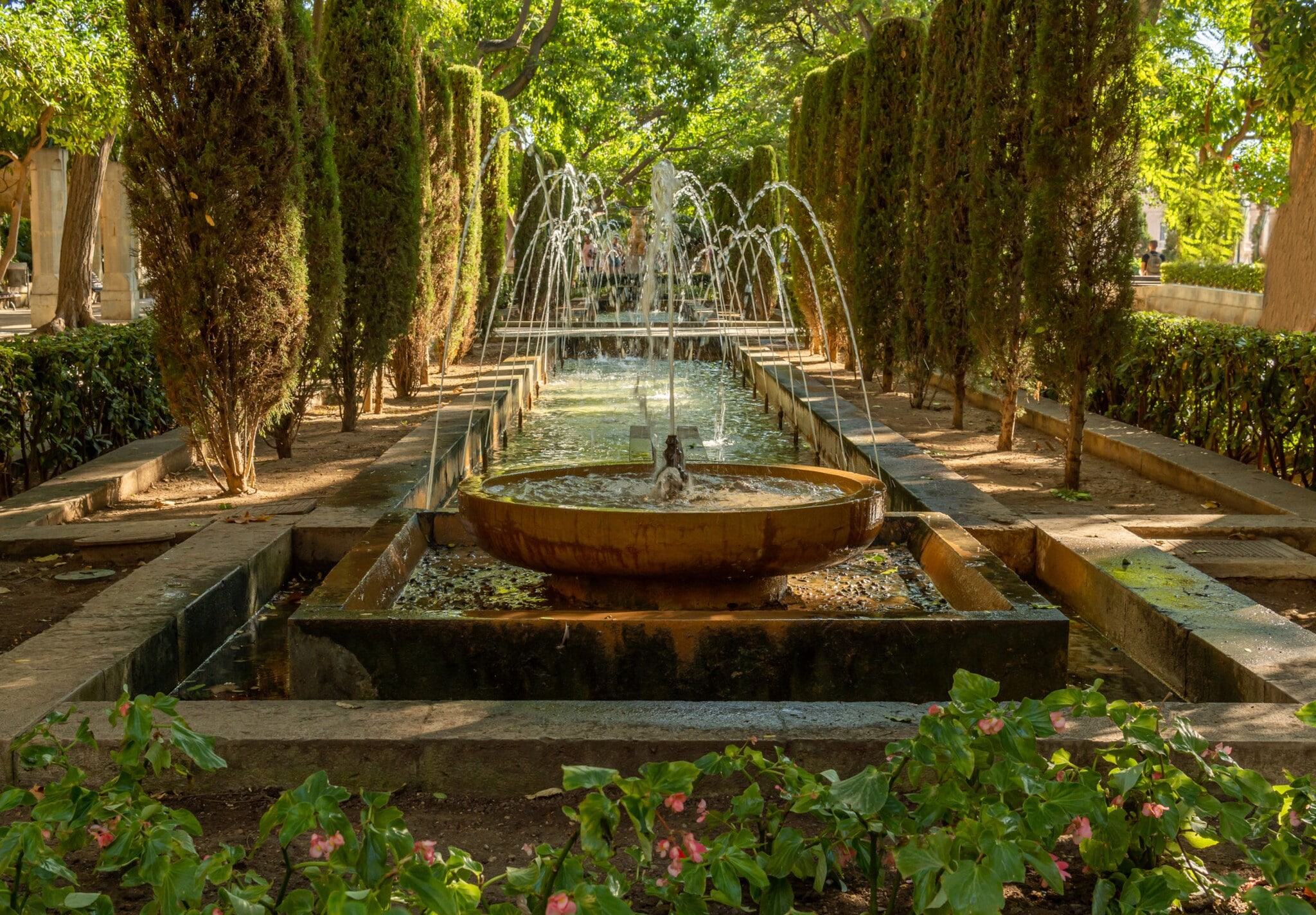 Springbrunnen in einer Parkanlage mit üppig grüner Vegetation. Springbrunnen in einer Parkanlage mit üppig grüner Vegetation.