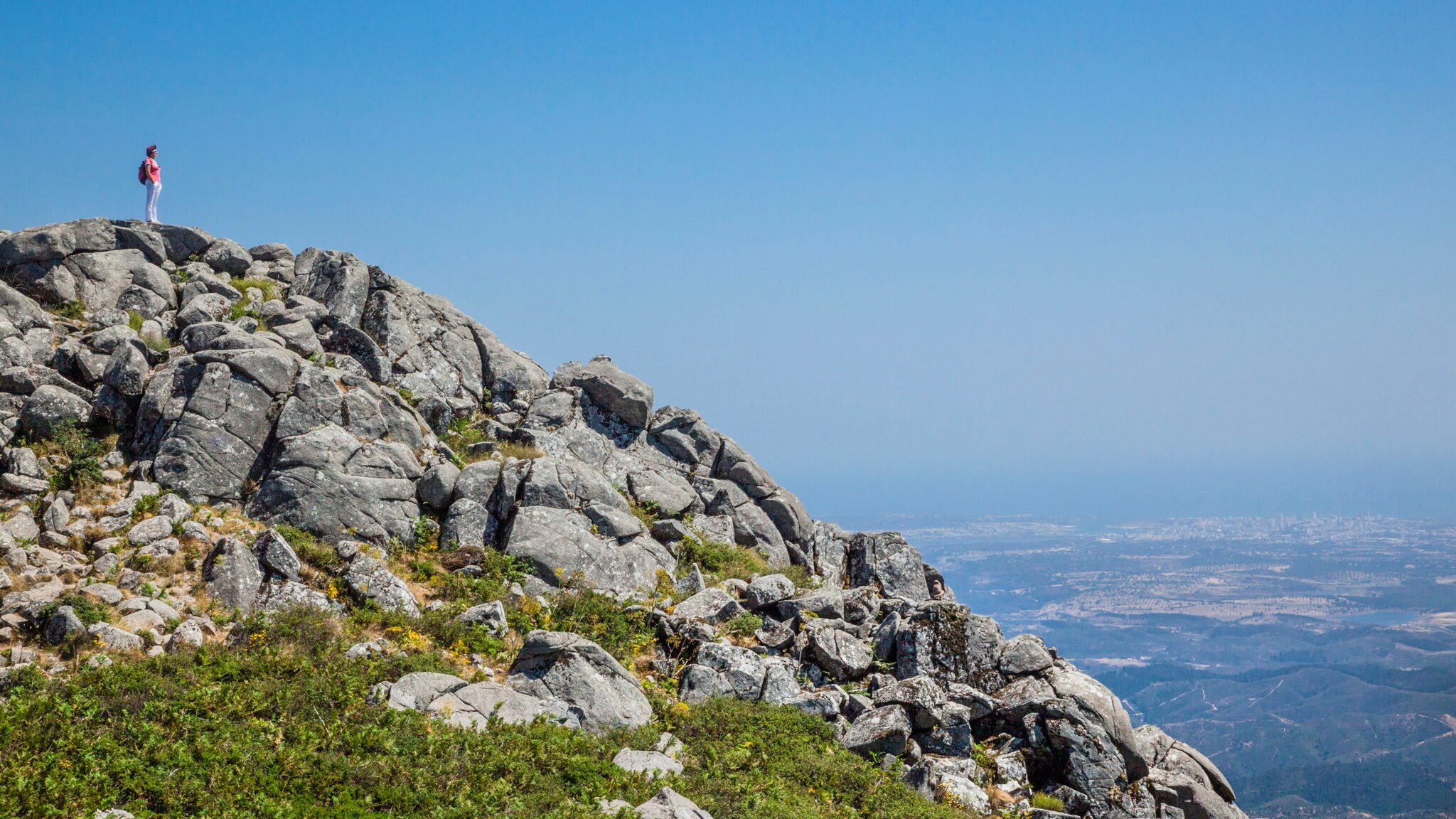 Eine Person auf dem felsigen Gipfel Fóia in der Serra de Monchique in Portugal. Eine Person auf dem felsigen Gipfel Fóia in der Serra de Monchique in Portugal.