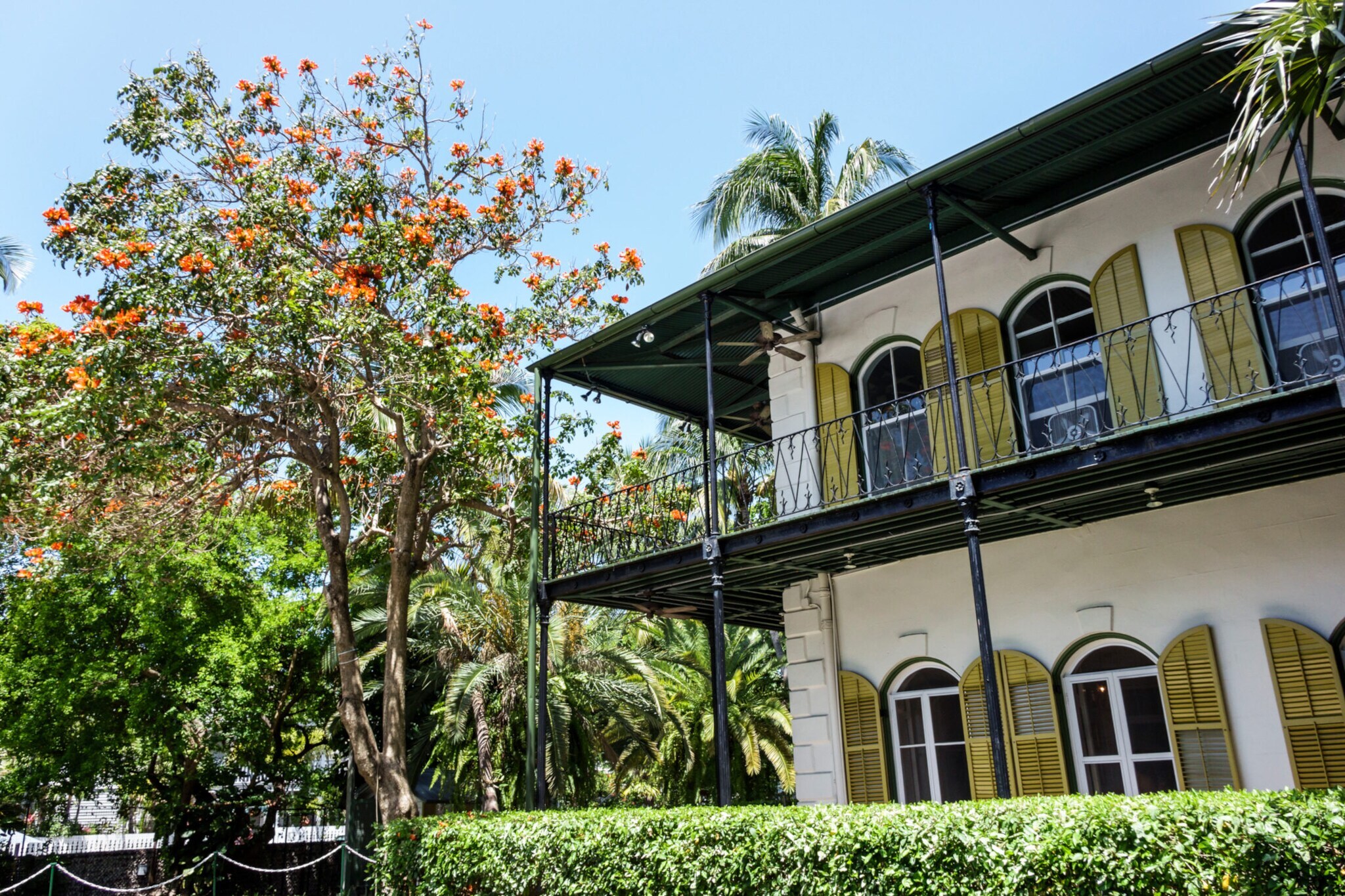 Historisches Haus im spanischen Kolonialstil, umgeben von einem Garten mit subtropischer Vegetation.