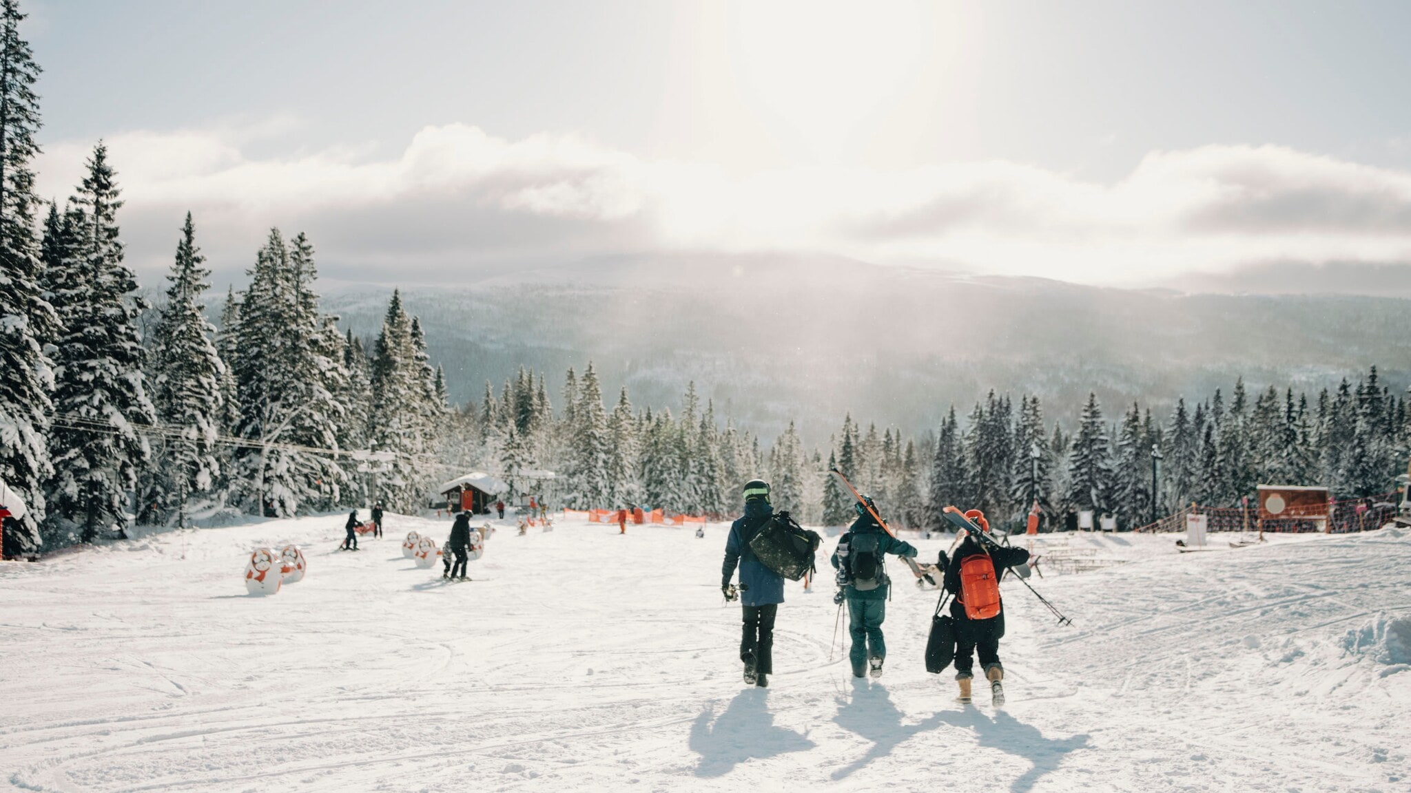 Drei unkenntliche Personen mit Skiausrüstung, die im Winter durch den Schnee in einem Skigebiet laufen. Drei unkenntliche Personen mit Skiausrüstung, die im Winter durch den Schnee in einem Skigebiet laufen.