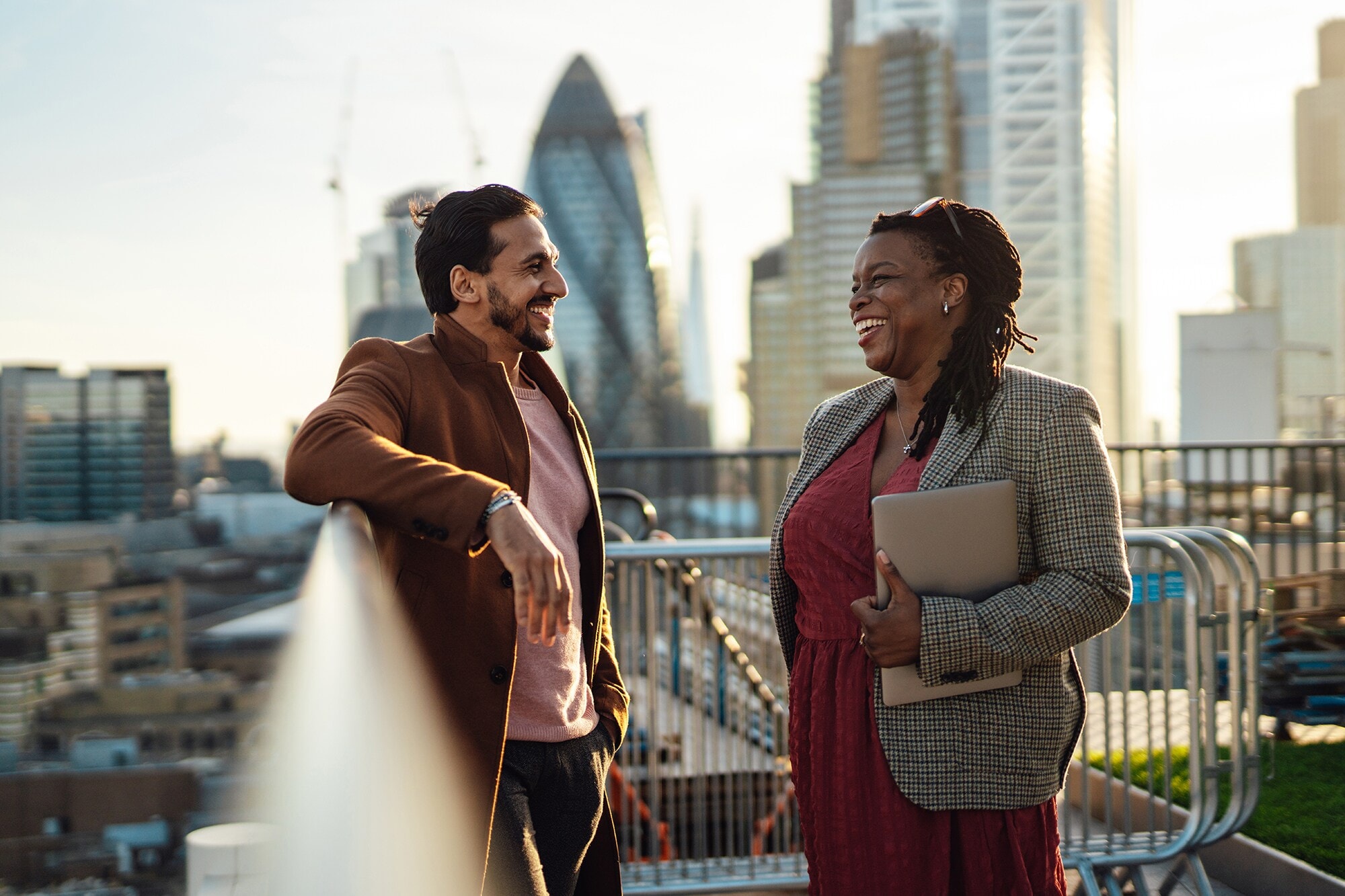 5 Event-Locations für Business-Meetings mit mehr Wow-Effekt Eine Geschäftsfrau und ein Geschäftsmann unterhalten sich auf einer Dachterasse in London.