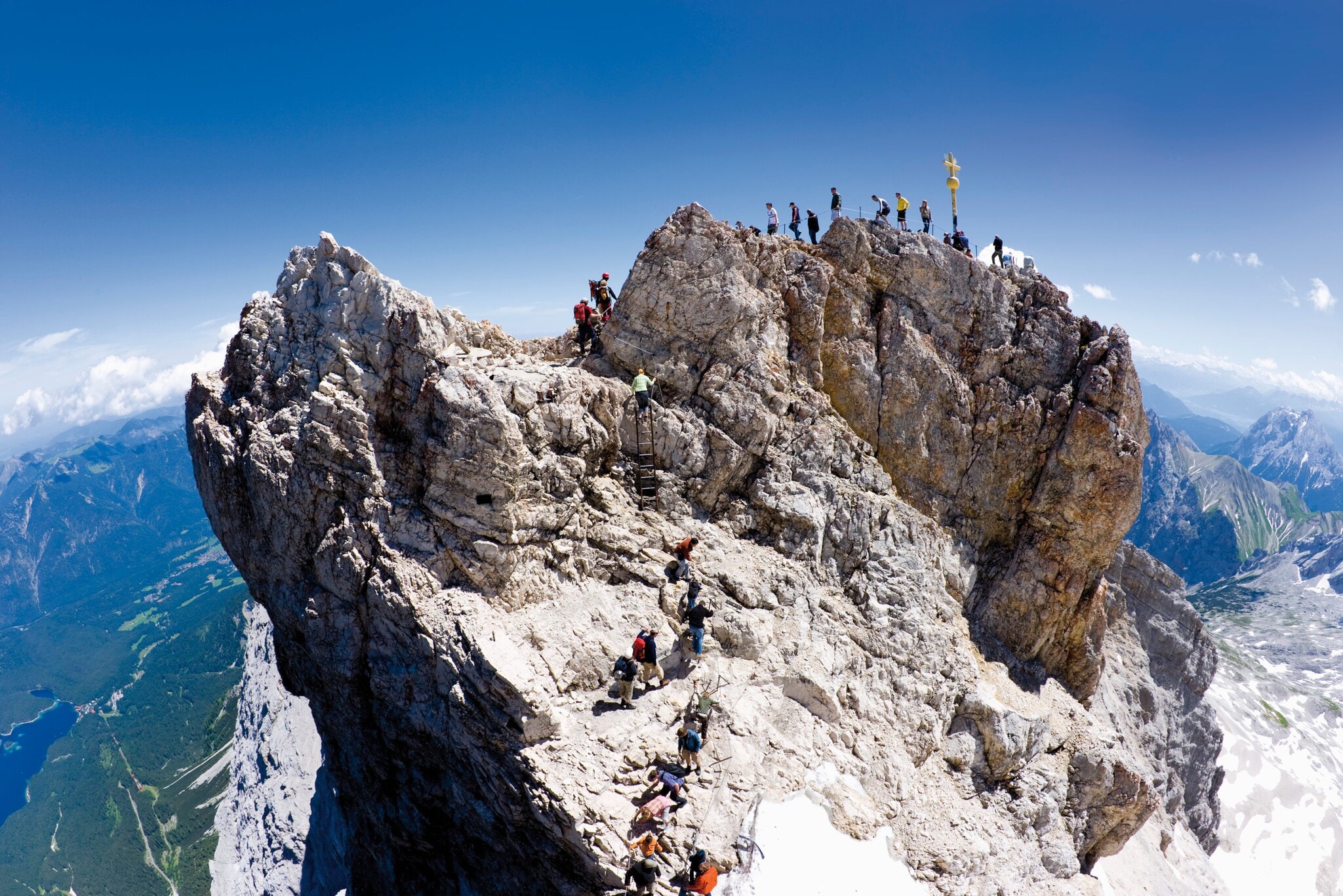 Wandernde auf dem Gipfel der Zugspitze bei blauem Himmel.