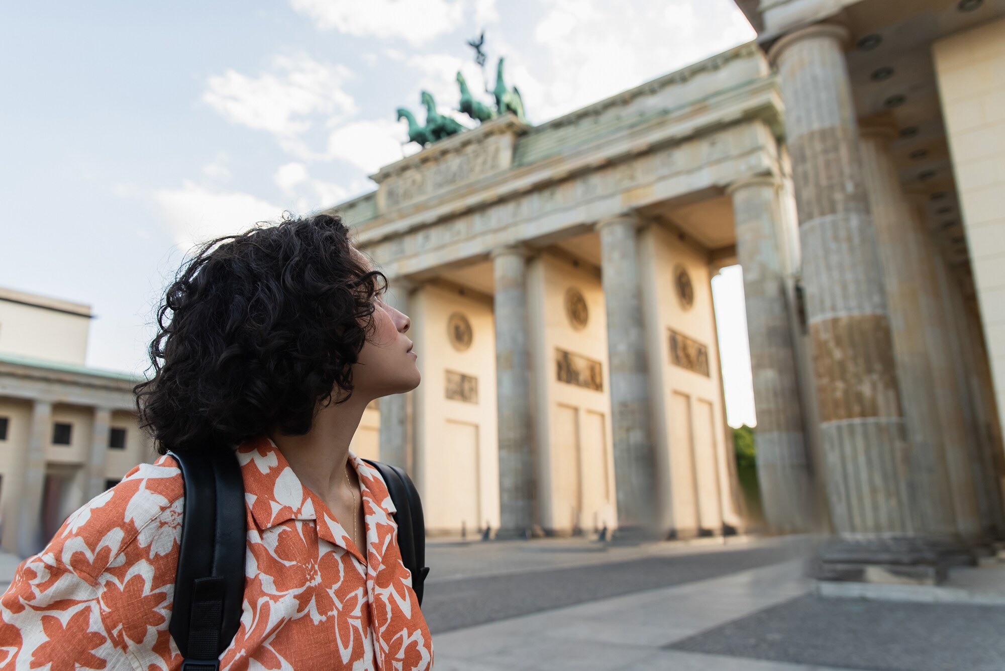Eine junge Frau schaut auf das Brandenburger Tor.