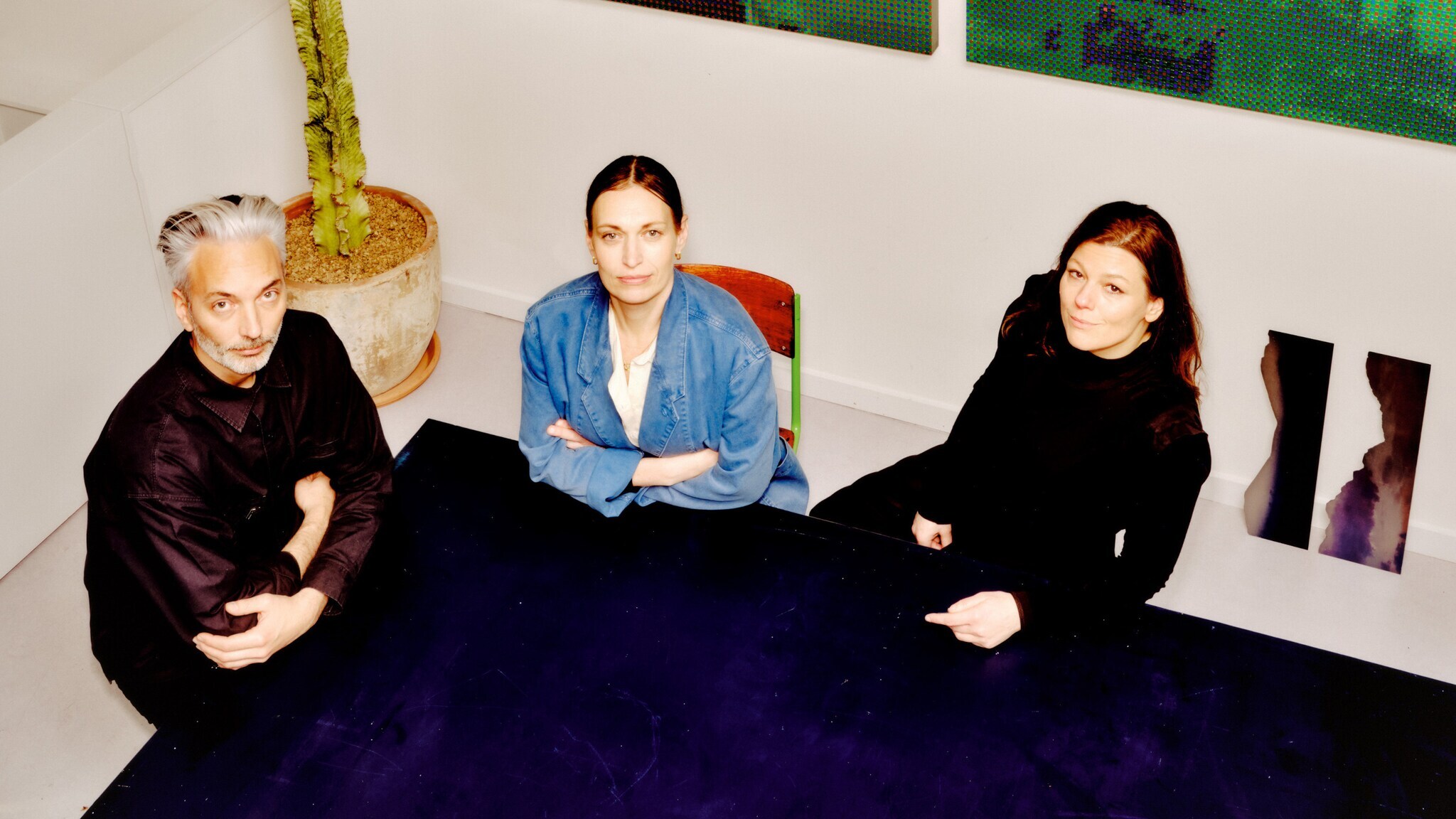 Blick von oben auf drei Personen an einem Tisch in einem Kunstatelier.