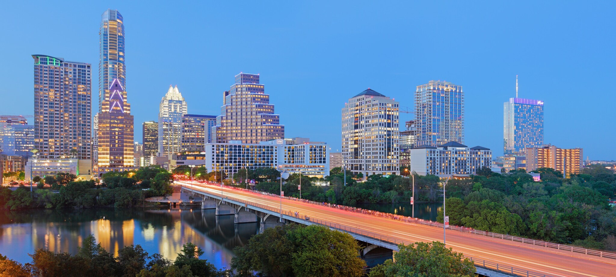 Beleuchtete Skyline von Austin mit Brücke über einem Fluss im Vordergrund in der Abenddämmerung. Beleuchtete Skyline von Austin mit Brücke über einem Fluss im Vordergrund in der Abenddämmerung.