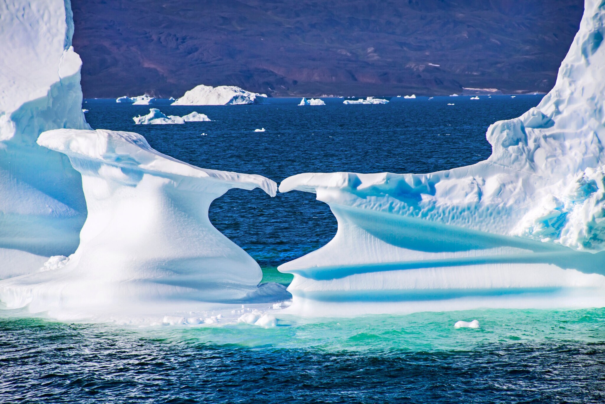 Zwei Eisschollen im Meer formen eine Herzform.