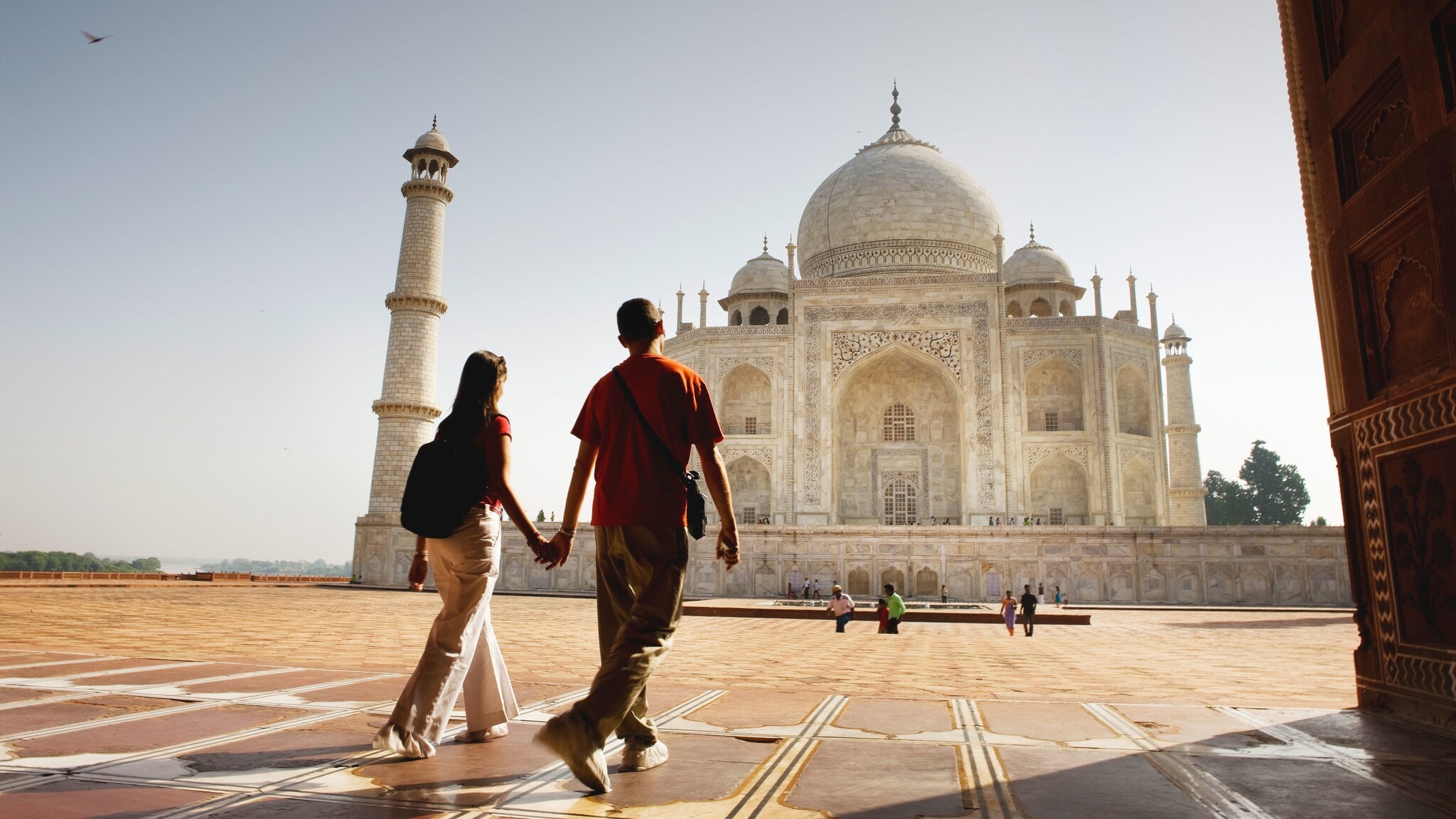 Rückansicht eines handhaltenden Paares auf dem Gelände der Taj Mahal Grabmoschee. Rückansicht eines handhaltenden Paares auf dem Gelände der Taj Mahal Grabmoschee.
