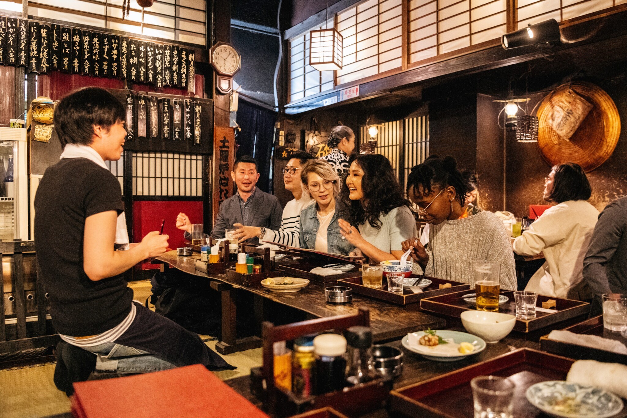 Mehrere Personen sitzen an einem Tresen in einem japanischen Restaurant. Mehrere Personen sitzen an einem Tresen in einem japanischen Restaurant.