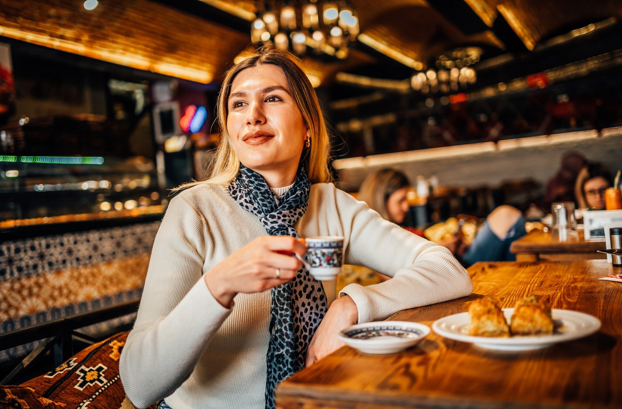 Eine Frau sitzt mit einem türkischen Mokka und Gebäck in einem Café. Eine Frau sitzt mit einem türkischen Mokka und Gebäck in einem Café.