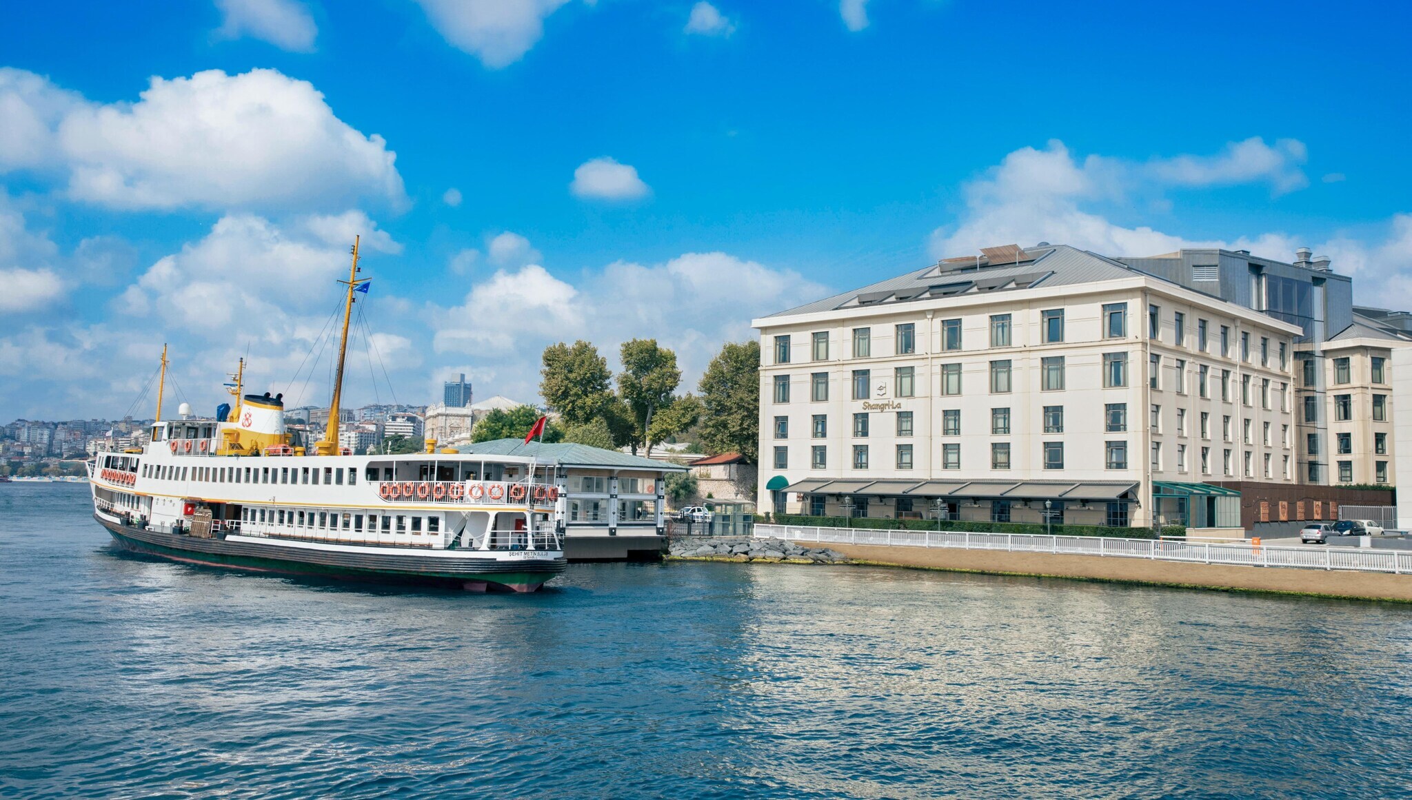 Ein Schiff vor einem weißen Hotelgebäude am Wasser in Istanbul.