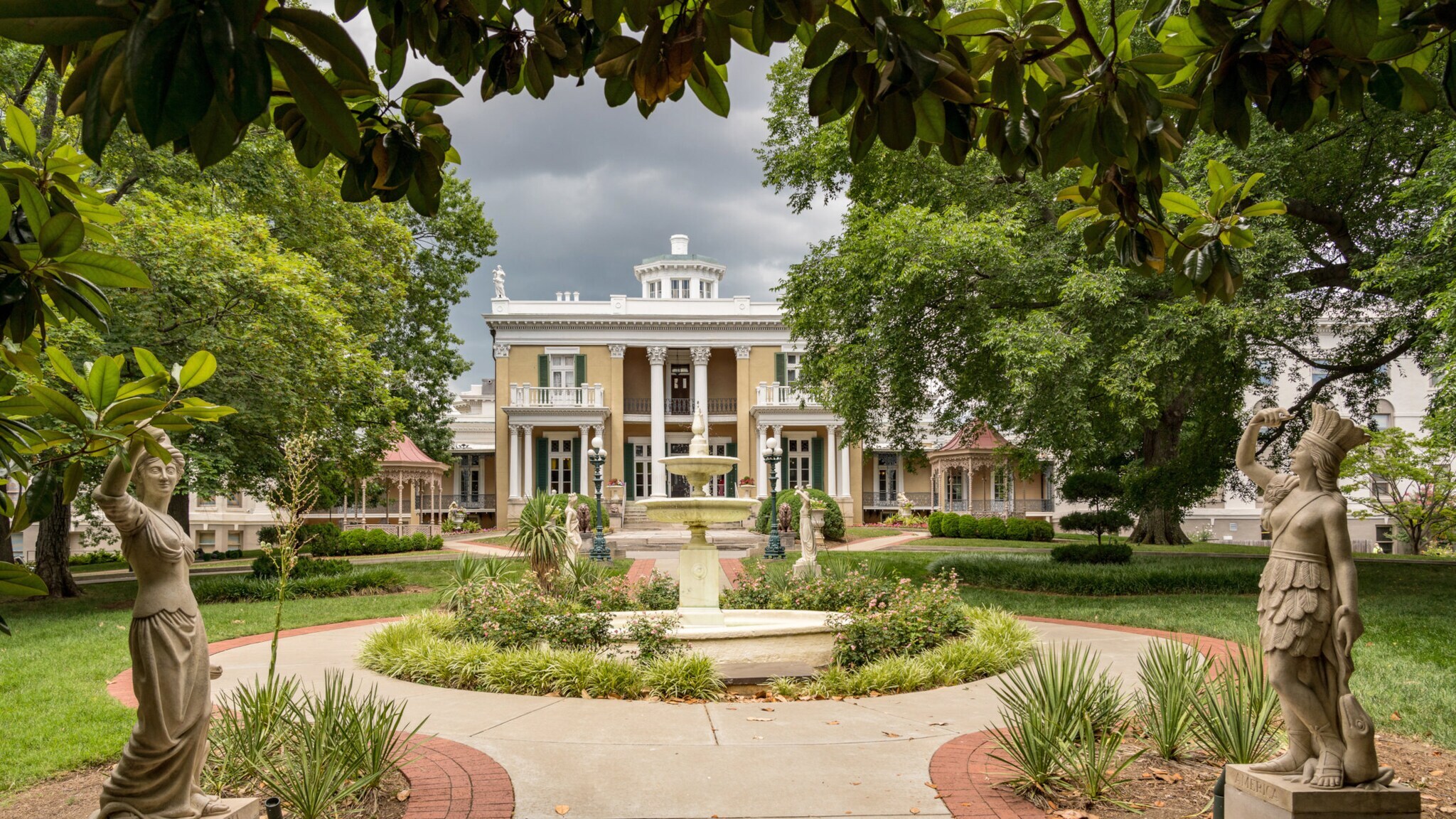 Gelbes Herrenhaus, umgeben von einer Parkanlage mit Statuen und Springbrunnen. Gelbes Herrenhaus, umgeben von einer Parkanlage mit Statuen und Springbrunnen.