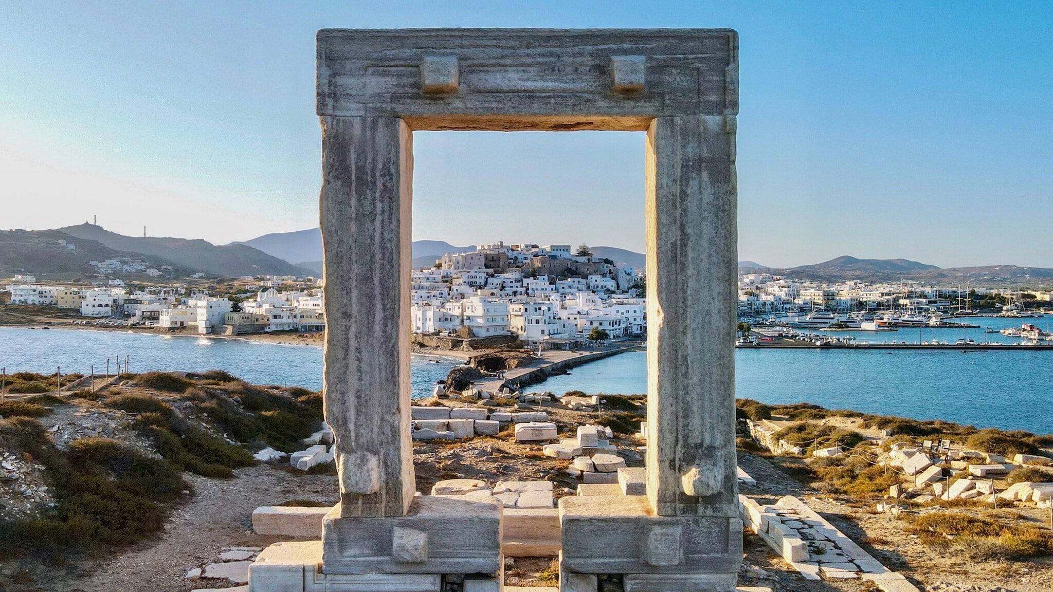 Blick auf die Stadt Naxos auf einer Insel durch ein Steintor in einer antiken Ruinenstätte auf einem Hügel. Blick auf die Stadt Naxos auf einer Insel durch ein Steintor in einer antiken Ruinenstätte auf einem Hügel.