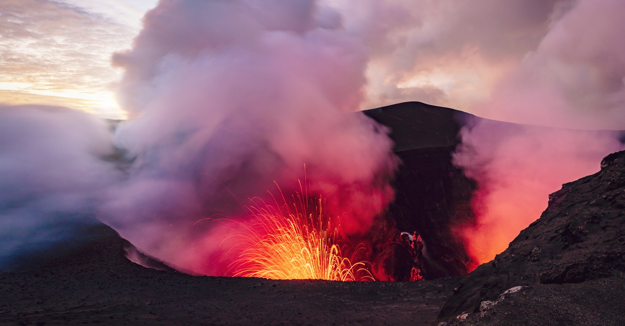 Rotglühende Funken und Dampf steigen aus einem Vulkankrater empor. Rotglühende Funken und Dampf steigen aus einem Vulkankrater empor.