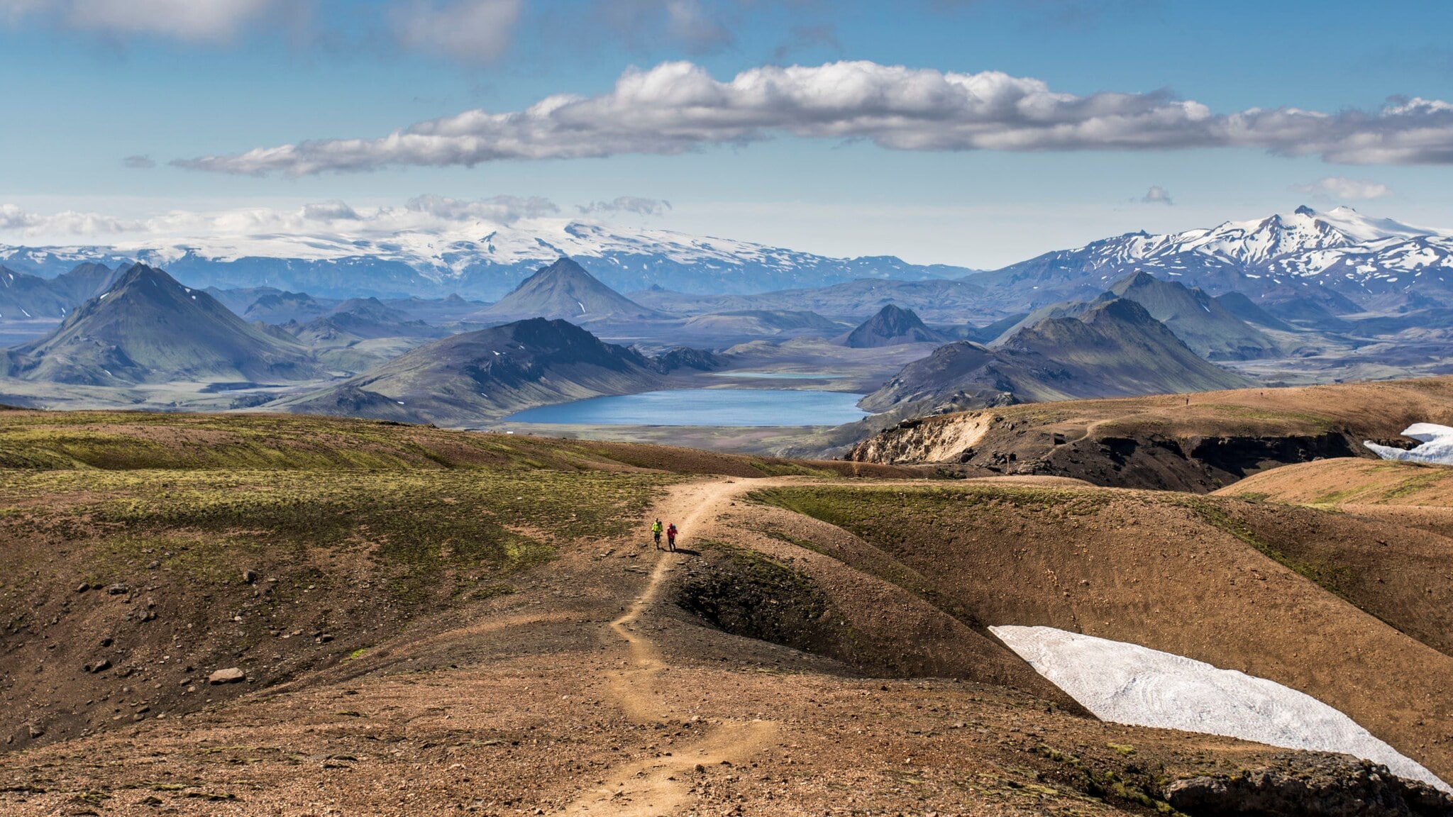 Landschaftspanorama in Island mit Trekkingpfad, auf dem sich zwei unkenntliche Personen befinden. Landschaftspanorama in Island mit Trekkingpfad, auf dem sich zwei unkenntliche Personen befinden.