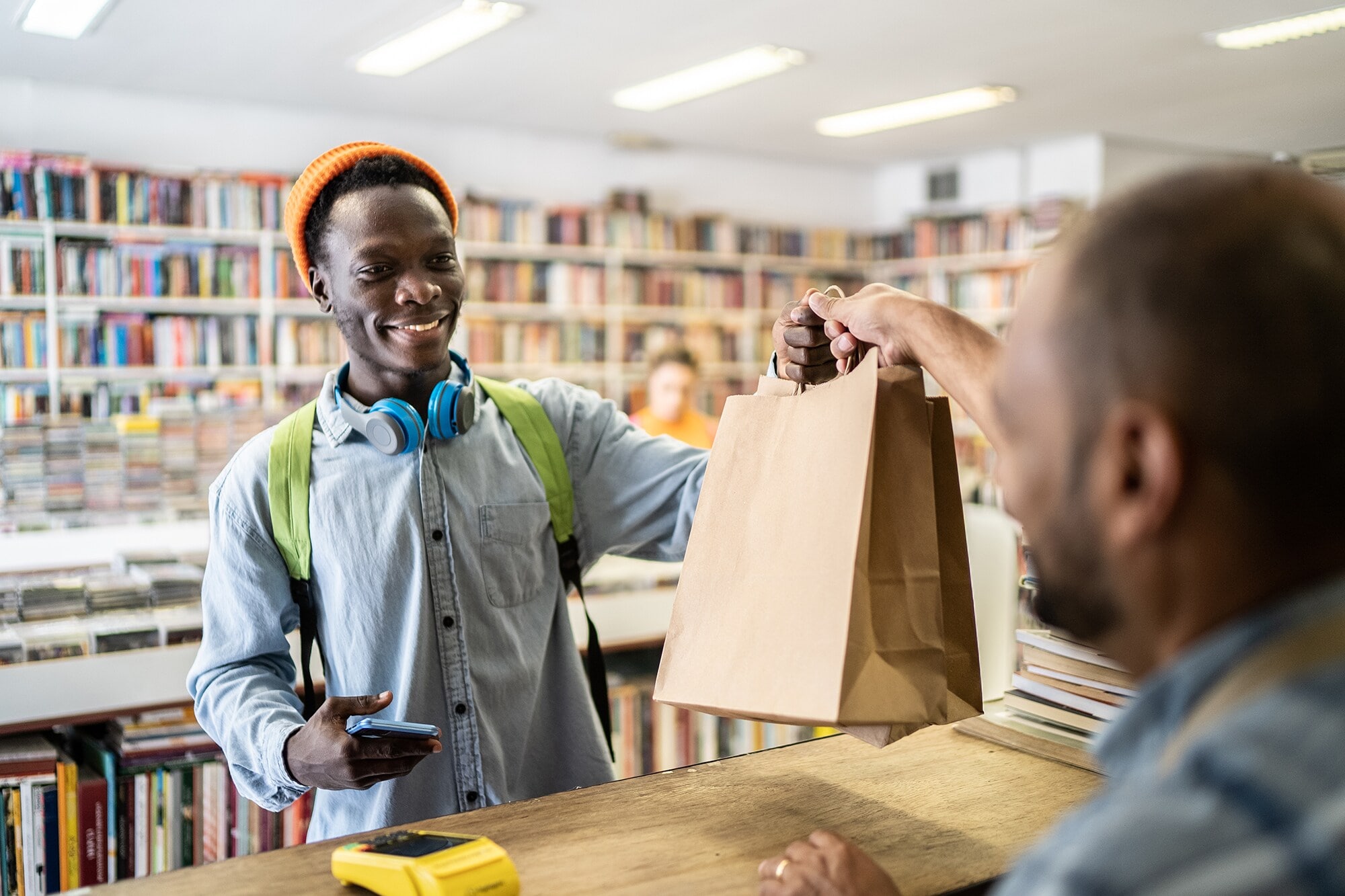 So wird dein Laden zum Erlebnis: 5 Wege zu mehr Customer Experience Ein junger Mann bezahlt seinen Einkauf in einem Buchladen.