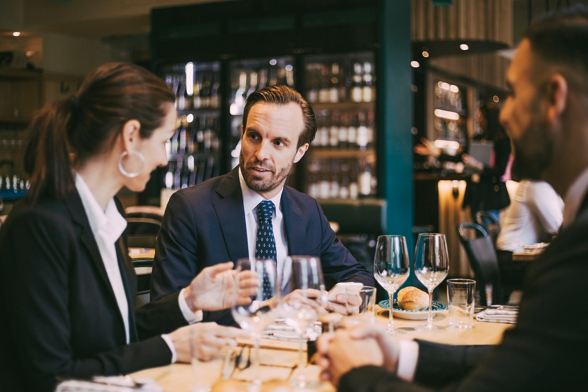 Mehrere Personen sitzen beim Business Lunch im gemütlichen italienischen Restaurant: Sie speisen und sind mitten im Small Talk.