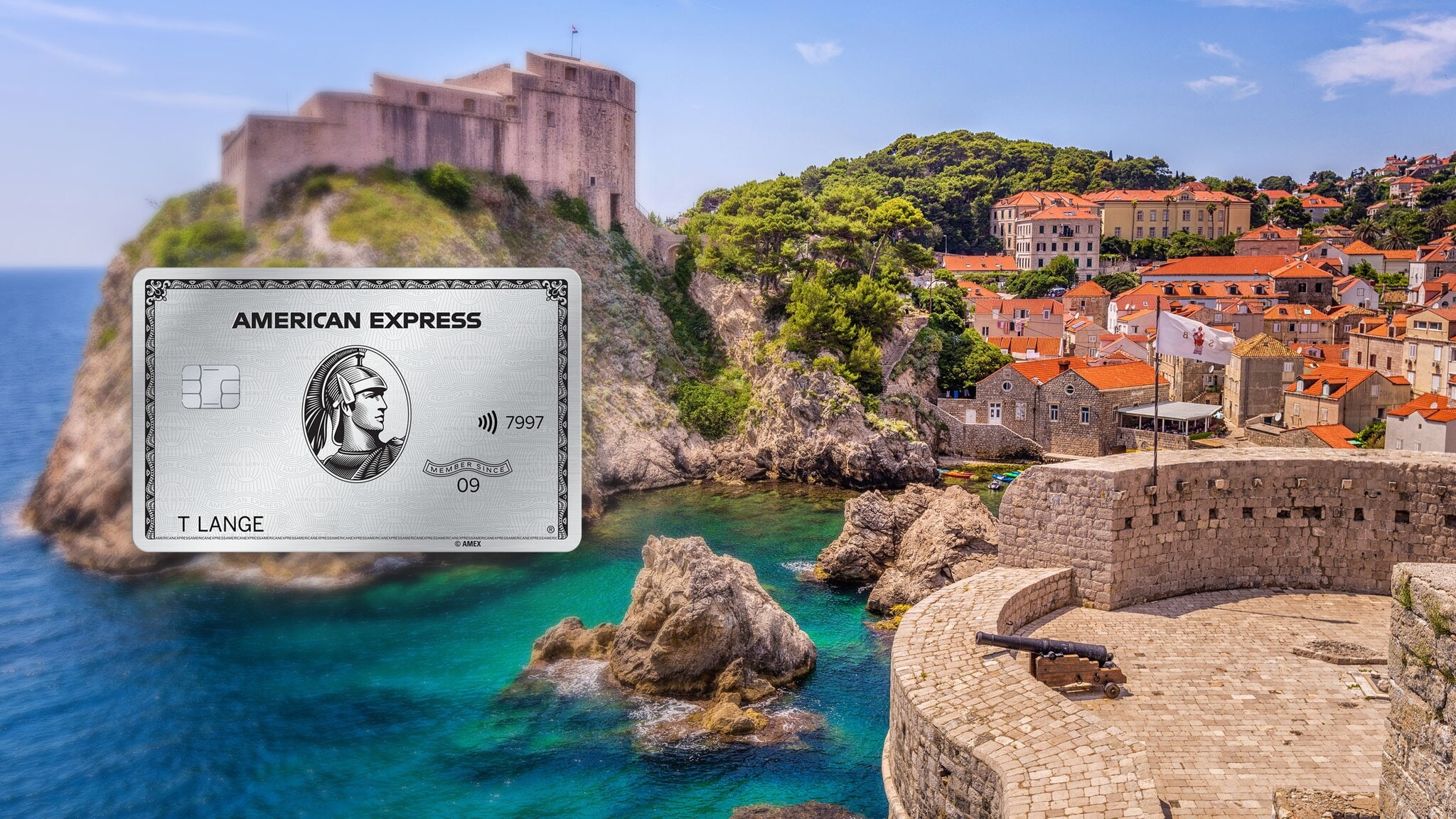 Ortschaft in einer Bucht mit türkisblauem Wasser an einer Felsküste mit historischen Festungen, im Vordergrund eine Aussichtsplattform mit Kanone auf einem Fort. Ortschaft in einer Bucht mit türkisblauem Wasser an einer Felsküste mit historischen Festungen, im Vordergrund eine Aussichtsplattform mit Kanone auf einem Fort.