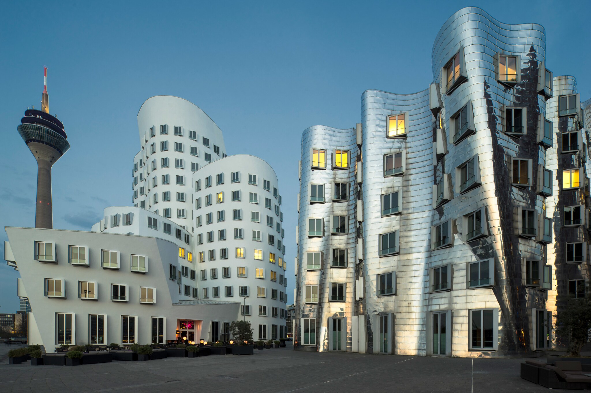 Mehrere moderne, organisch geformte Gebäude, dahinter ein Fernsehturm.