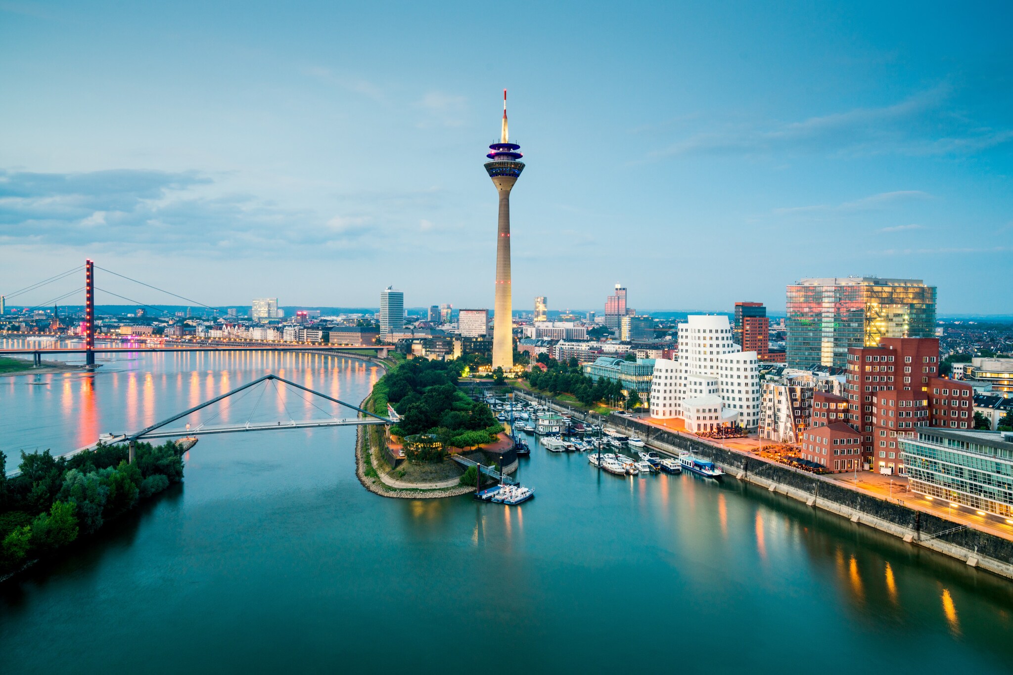 Skyline von Düsseldorf mit Fernsehturm am Hafen mit modernen Gebäuden in der Abenddämmerung.