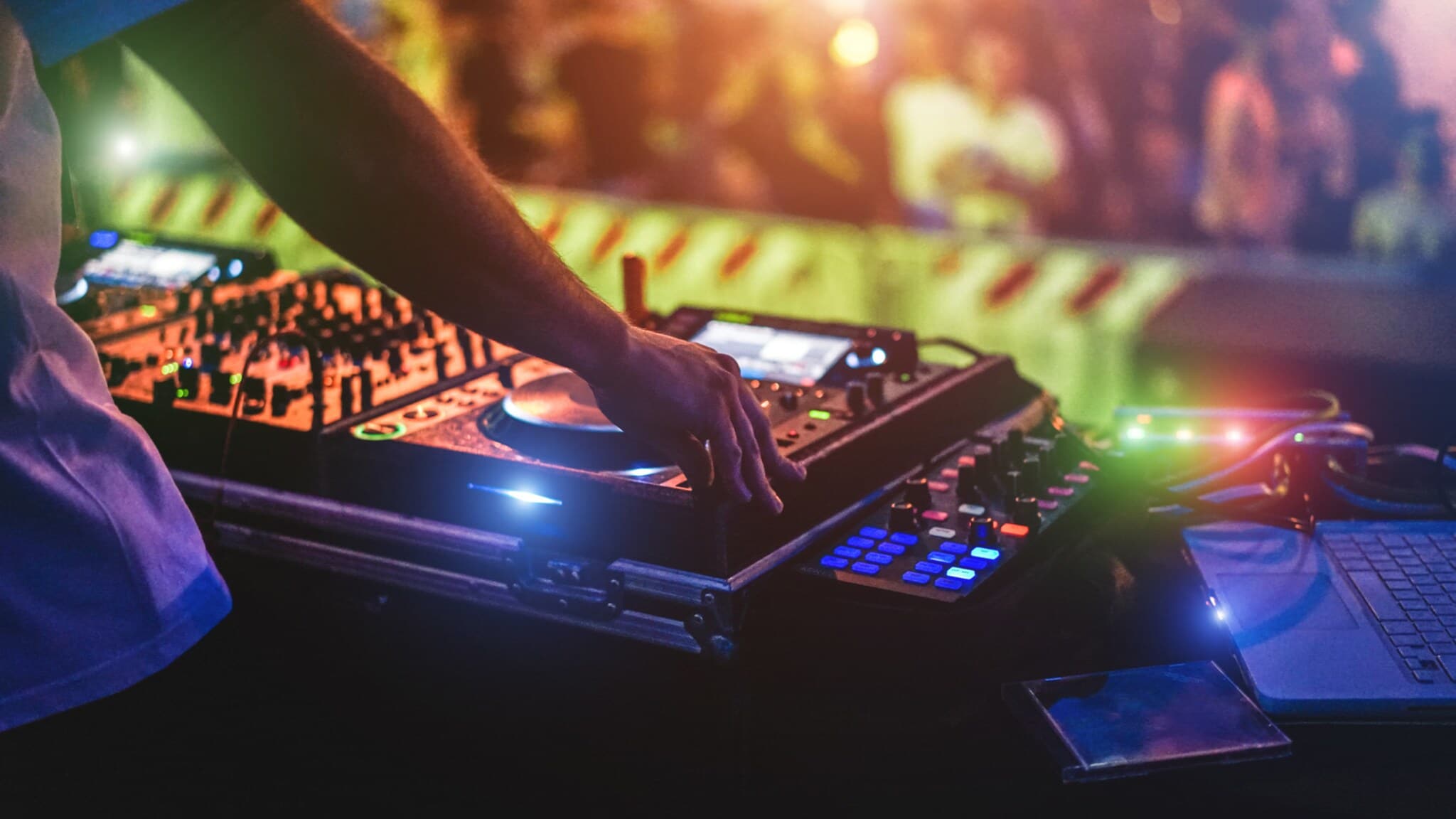 Eine unkenntliche Person, die an einem DJ Pult auf einer Bühne steht. Eine unkenntliche Person, die an einem DJ Pult auf einer Bühne steht.