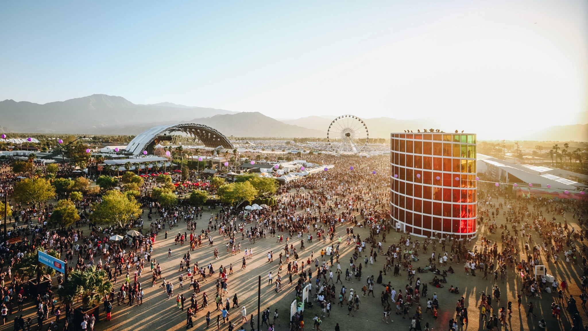 Luftaufnahme über das Gelände des Coachella Festivals mit vielen Personen, einer Bühne und einem Riesenrad.