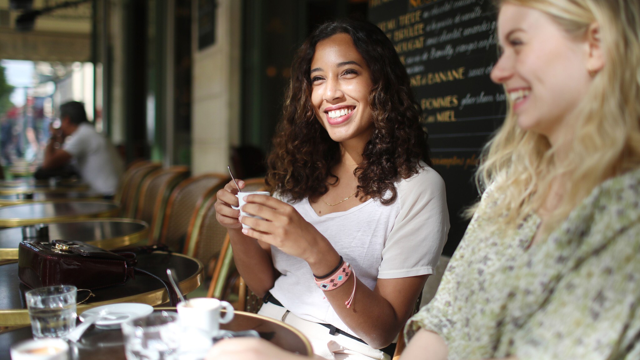 Zwei gut gelaunte Frauen sitzen beim Kaffeetrinken auf der Terrasse eines französischen Bistrots. Zwei gut gelaunte Frauen sitzen beim Kaffeetrinken auf der Terrasse eines französischen Bistrots.