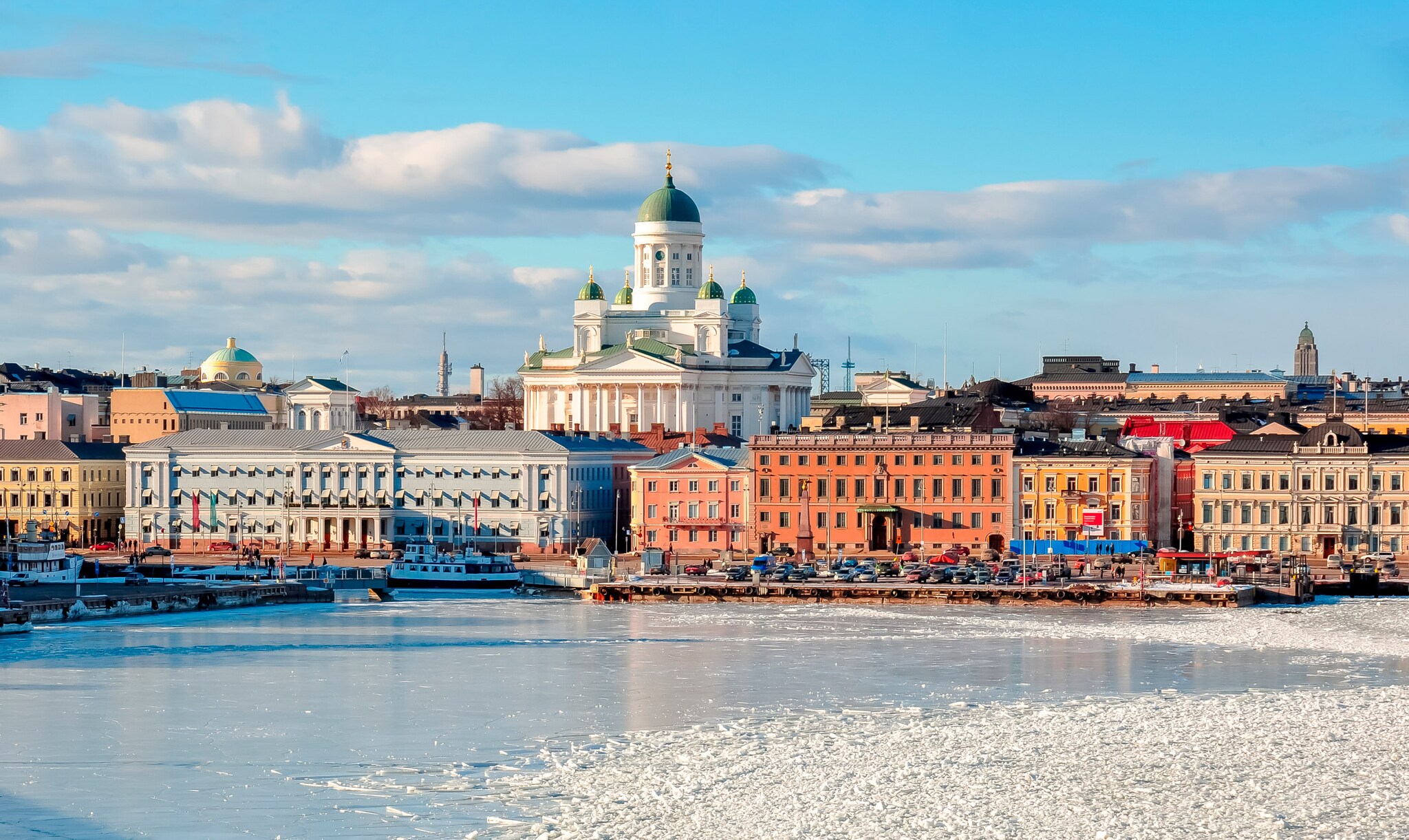 Stadtpanorama von Helsinki mit Dom an einer zugefrorenen Wasserfläche im Vordergrund.