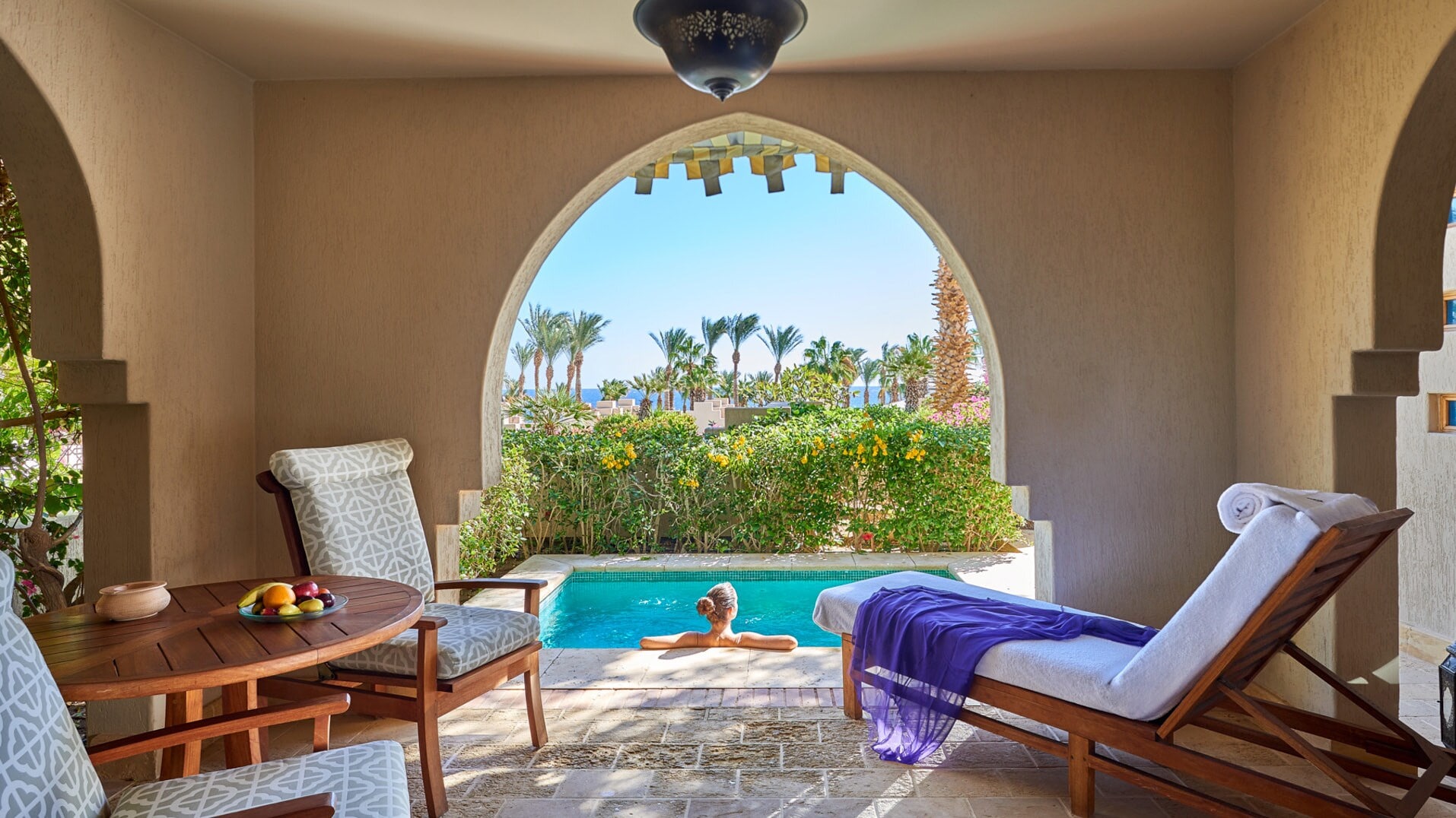 Rückansicht einer Frau in einem Privatpool auf der Terrasse einer Hotelsuite. Rückansicht einer Frau in einem Privatpool auf der Terrasse einer Hotelsuite.
